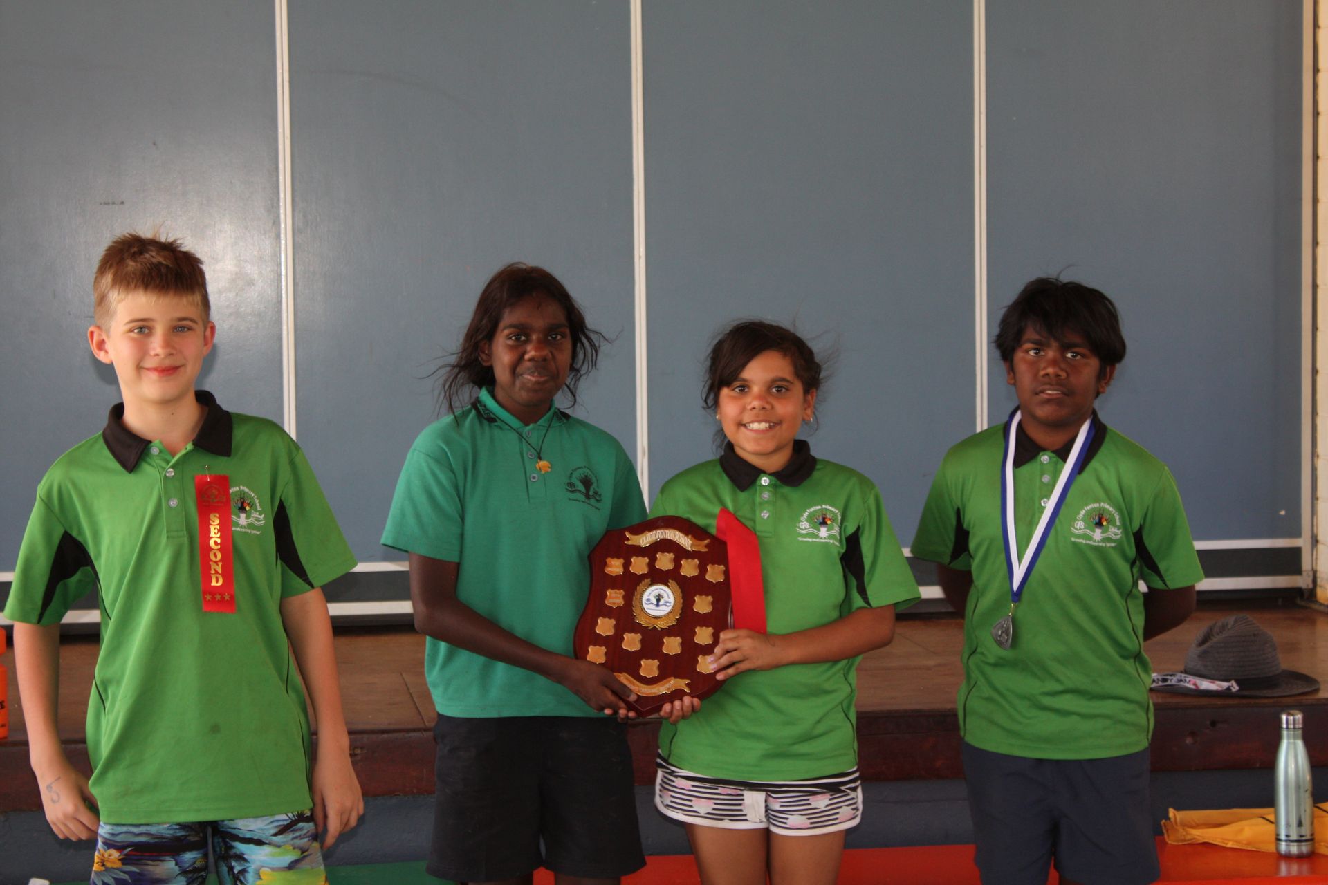 A group of young people in green shirts holding a plaque