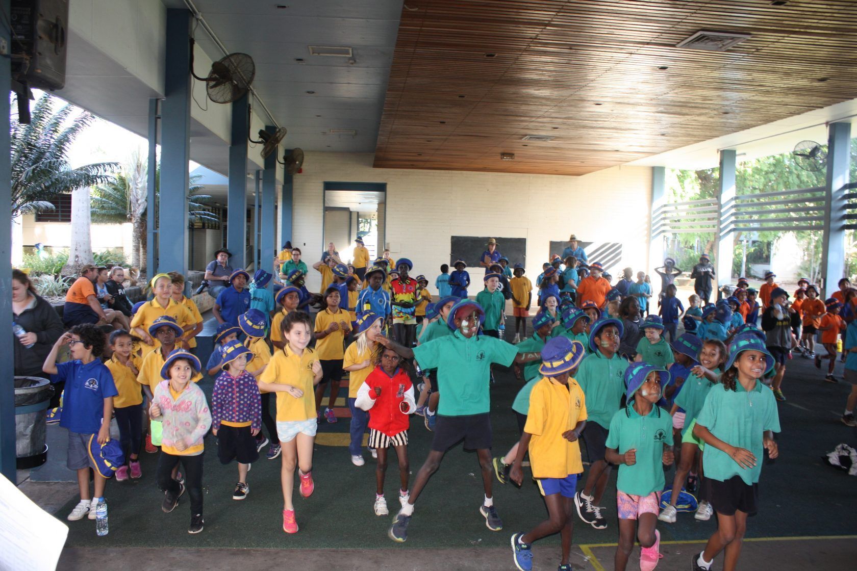 A large group of children are running in a gym
