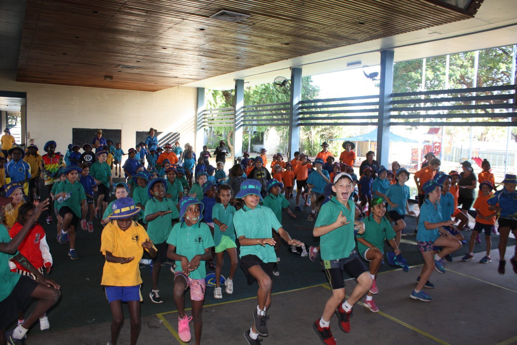 A large group of children are dancing in a gym.