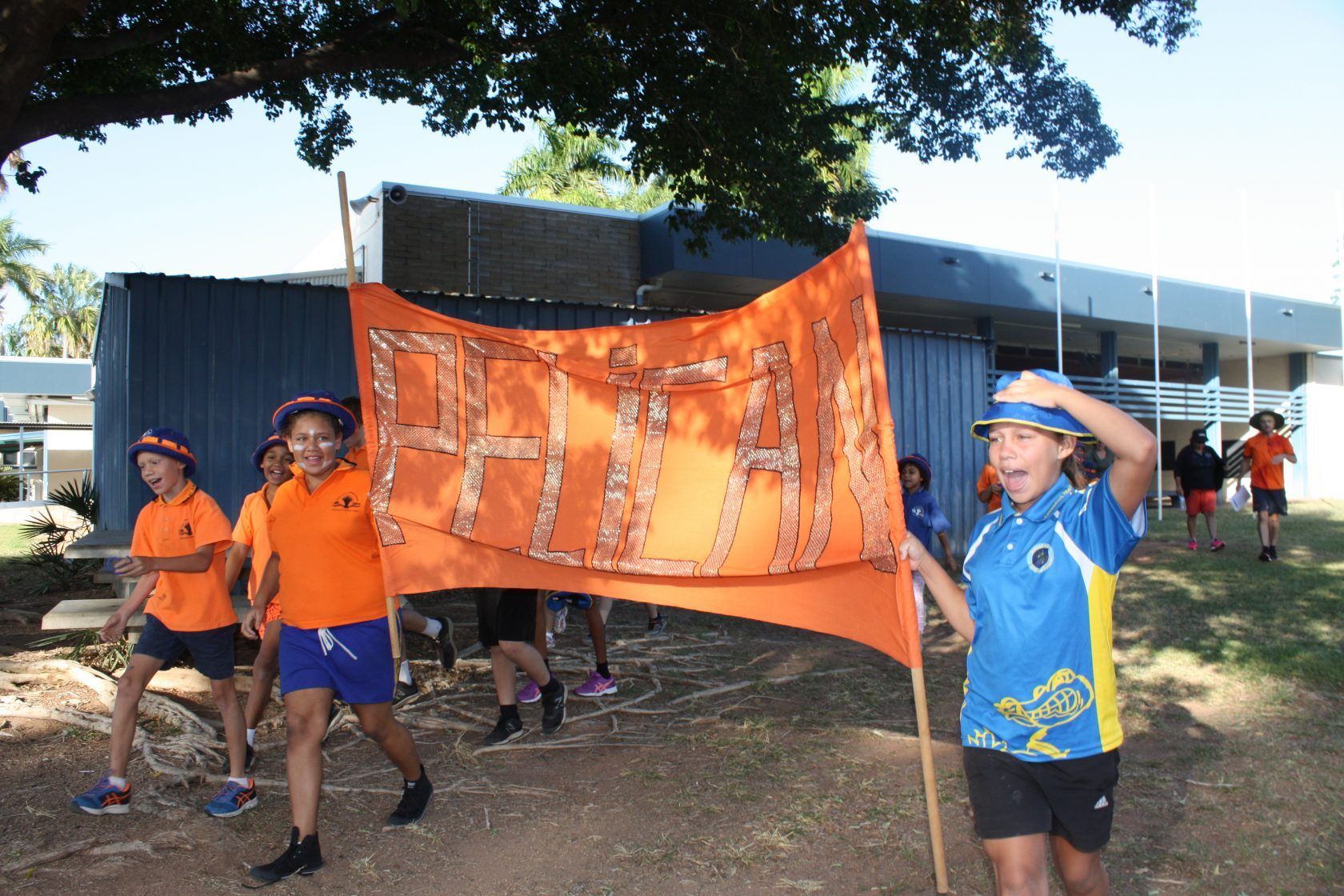 A group of children are holding a large orange banner that says ' eh ' on it