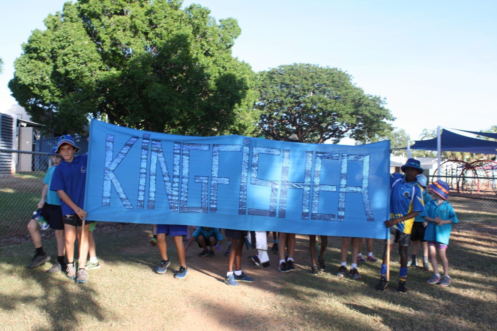 A group of children are holding a blue banner that says kingfisher