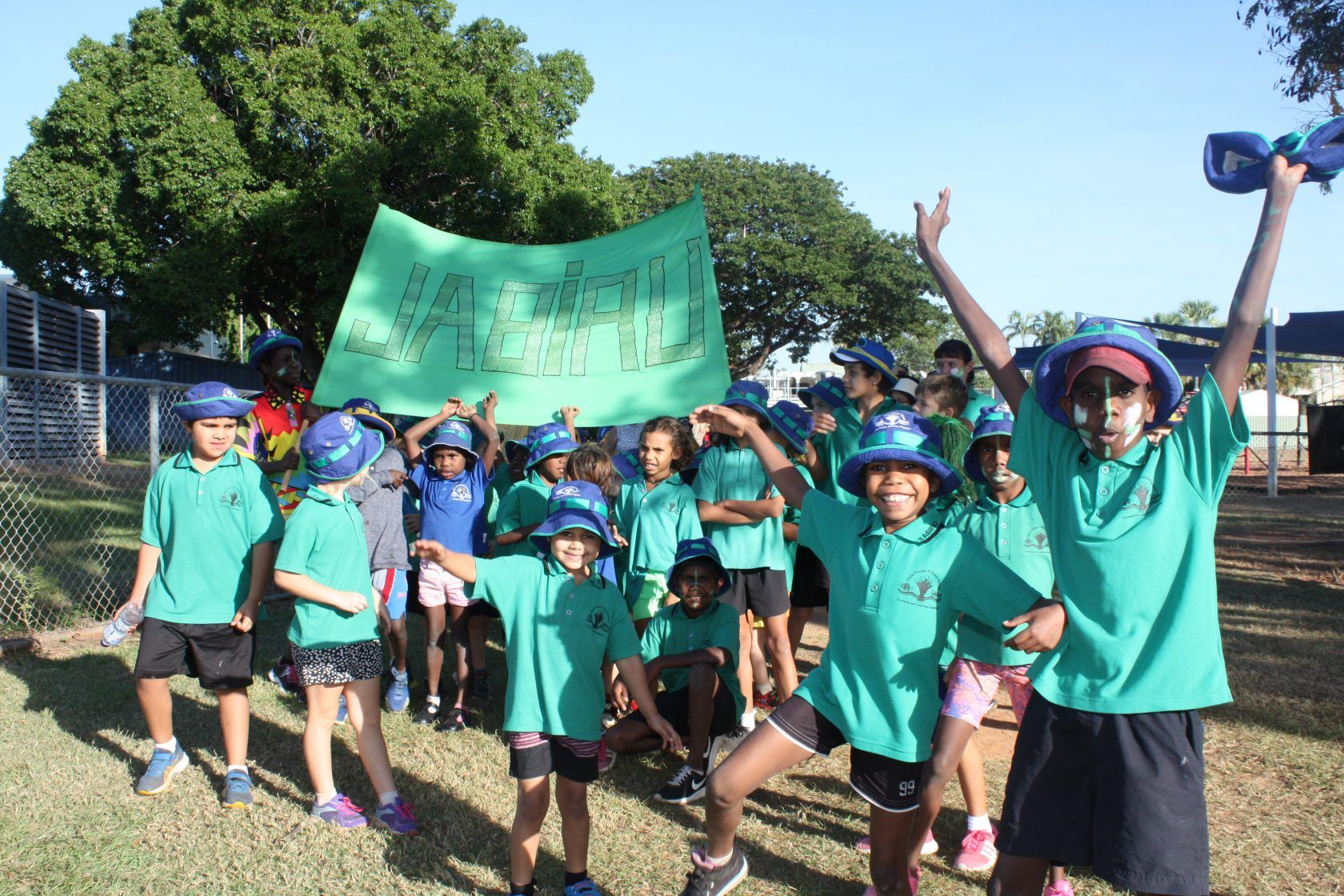 A group of children in green shirts are holding a green sign