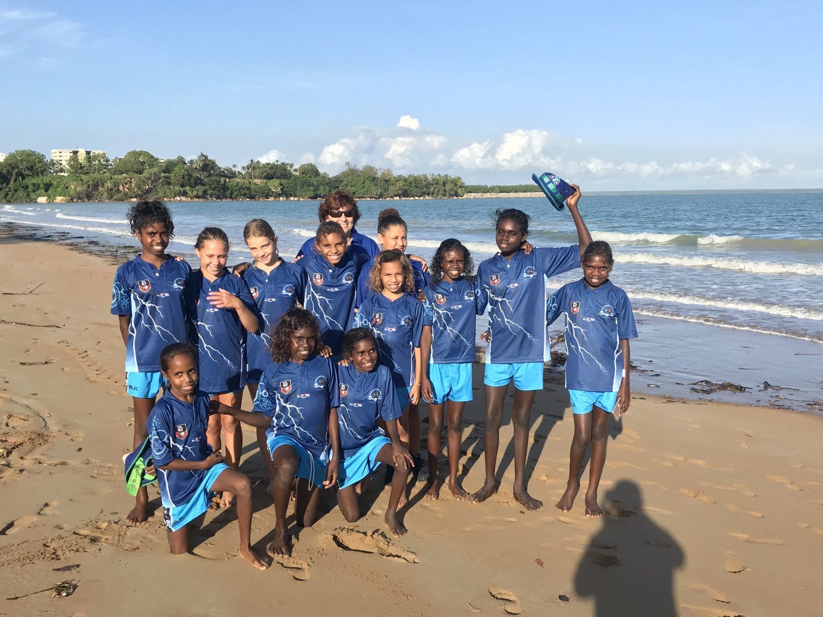 A group of children are posing for a picture on the beach.