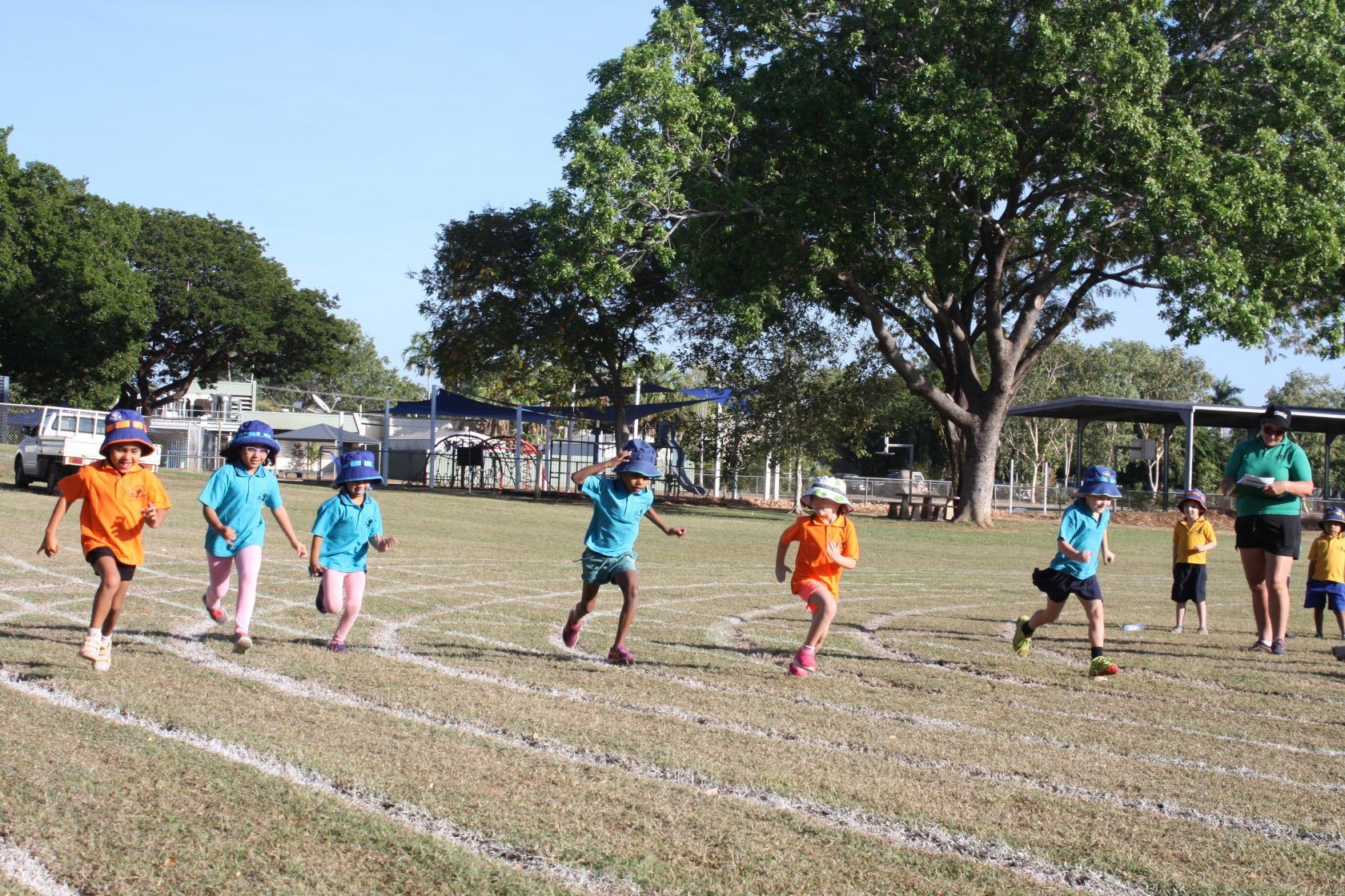 A group of children are running on a track in a field