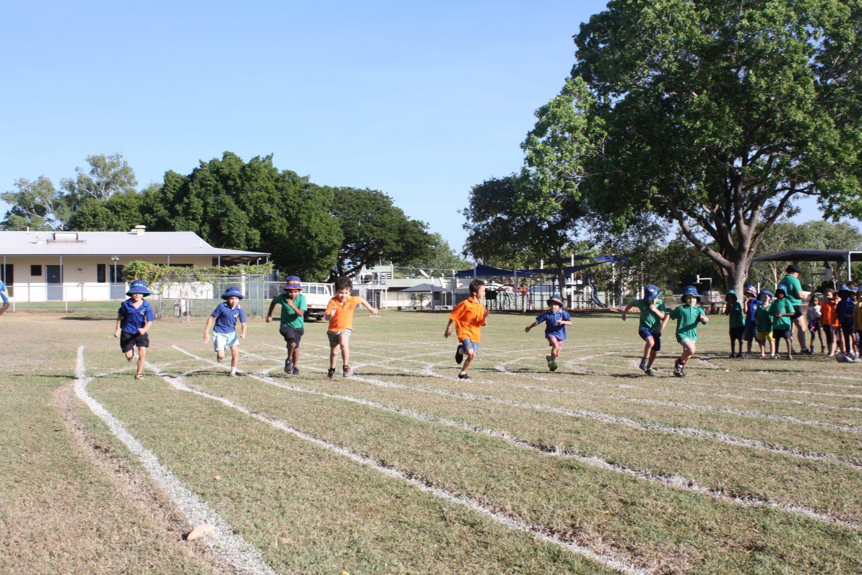 A group of children are running on a track in a field