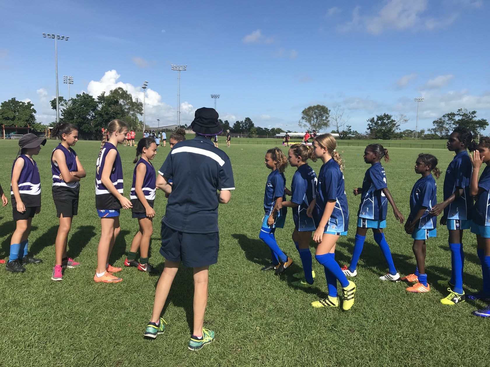 A group of young girls are standing in a field talking to each other.