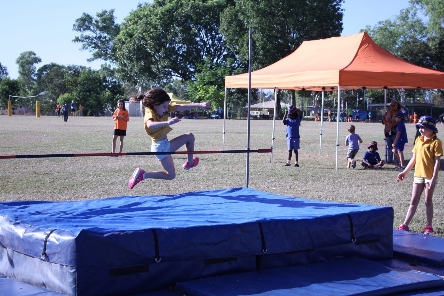 A young girl is jumping over a high jump bar
