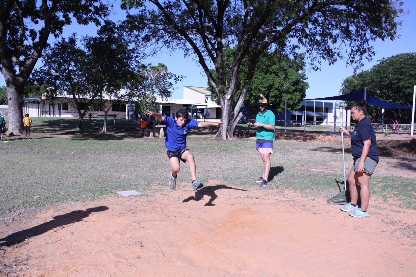 A boy is throwing a frisbee in a field while a woman watches.