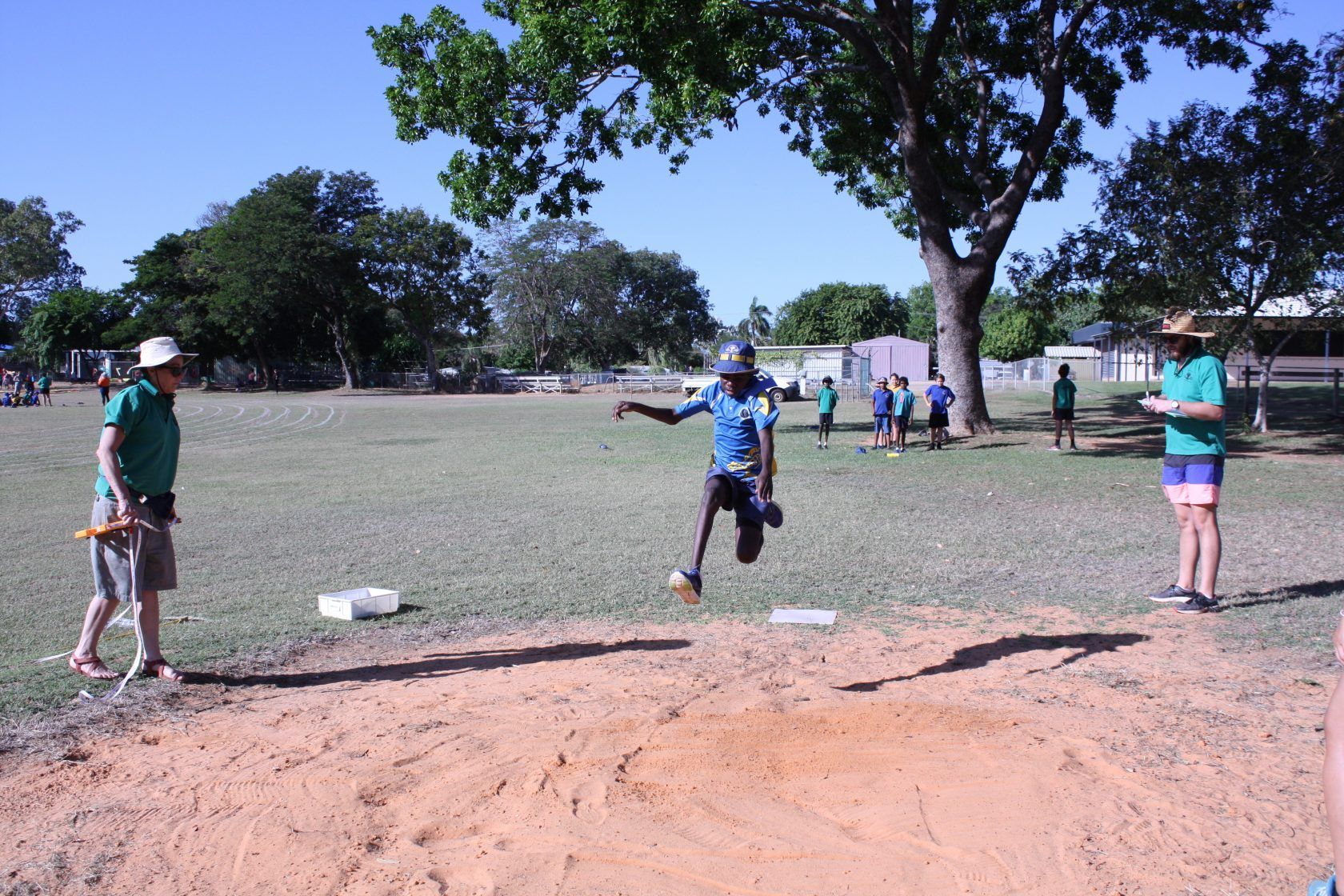 A man in a blue shirt is jumping in the air