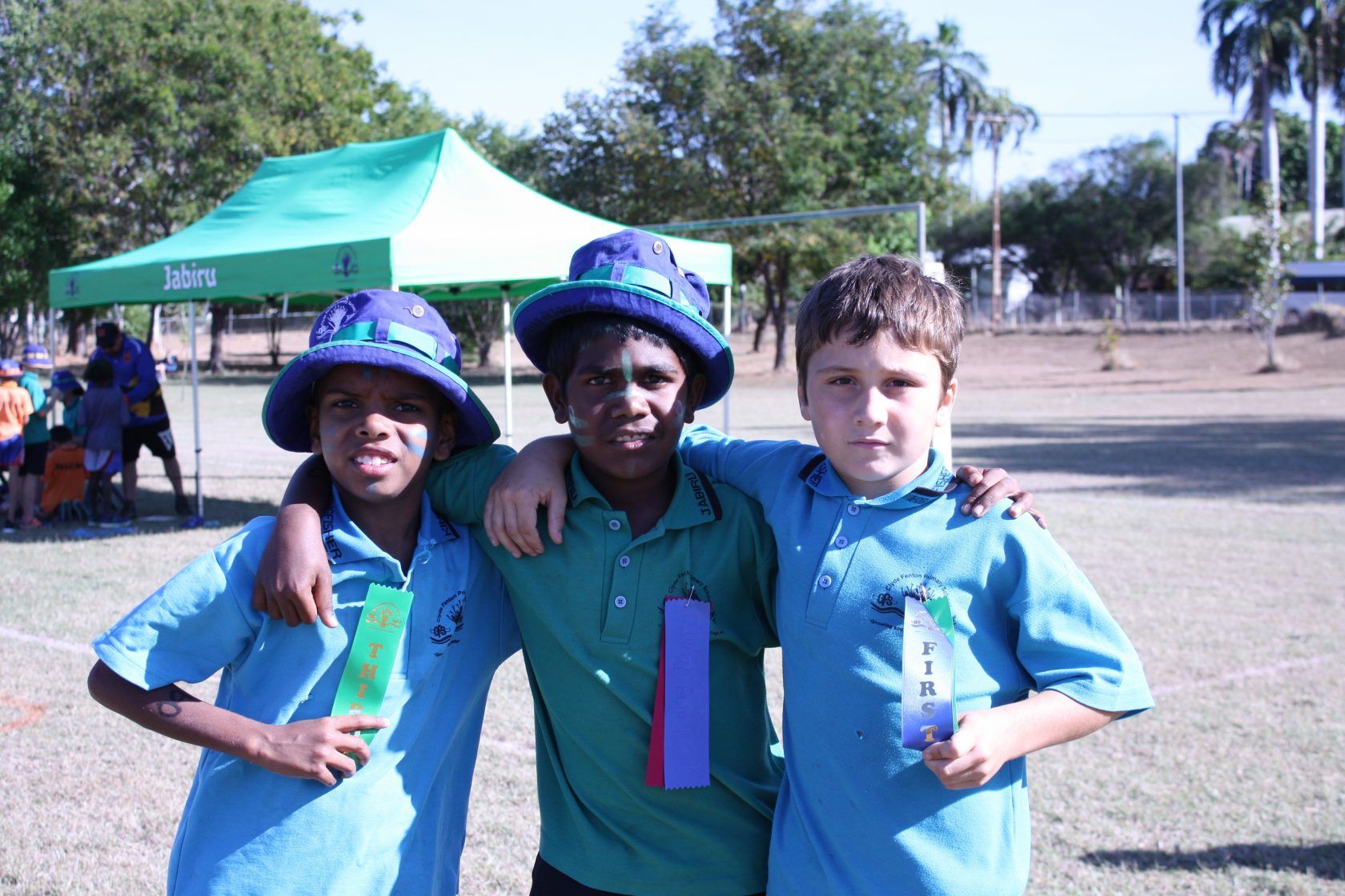 Three young boys posing for a picture in front of a green tent