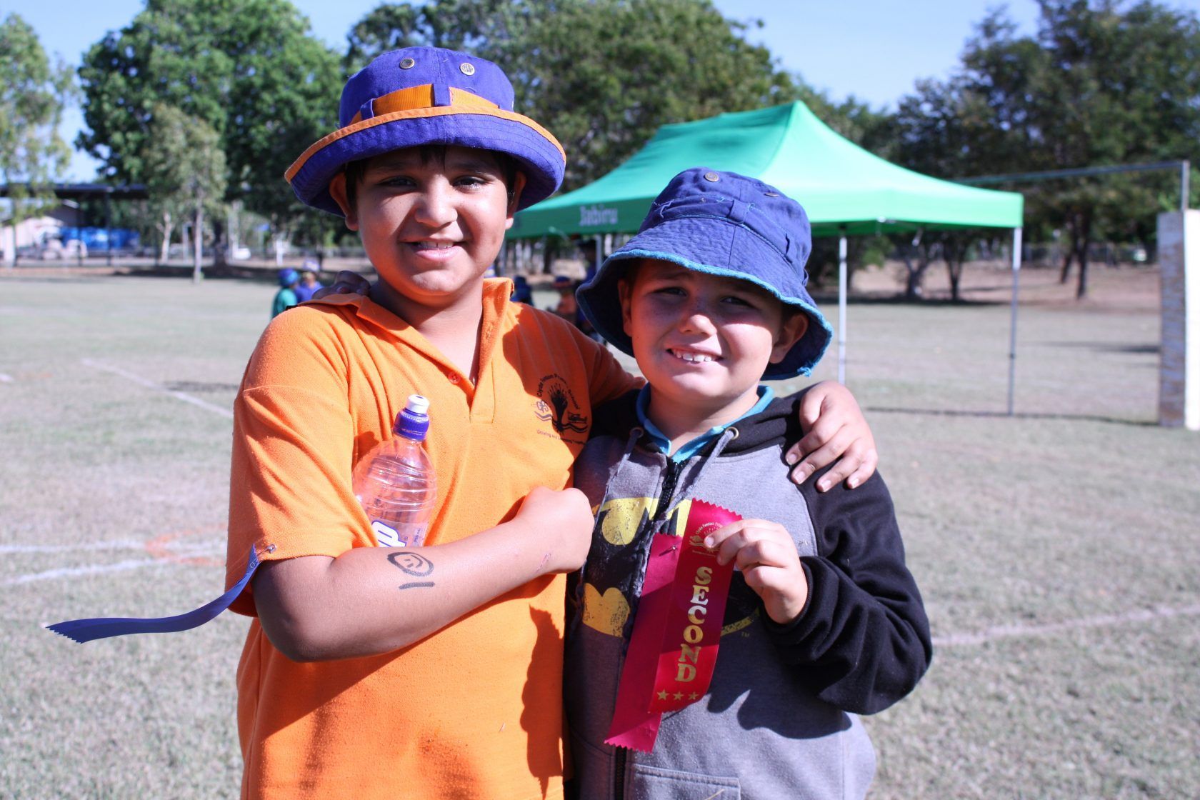 Two young boys are posing for a picture in a field