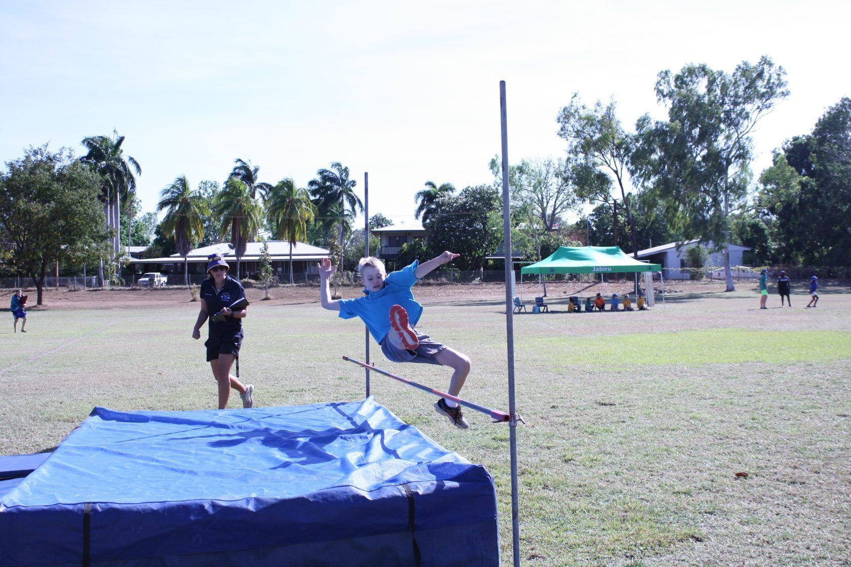 A boy is jumping over a pole in a field