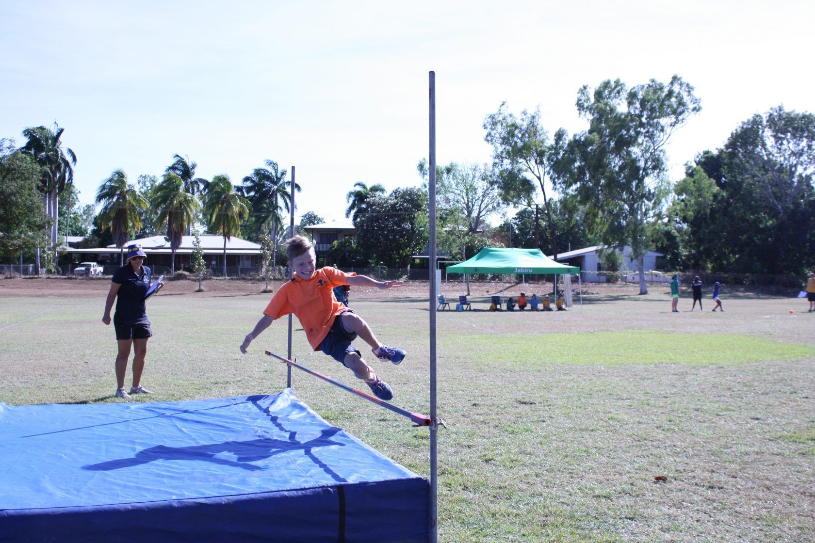 A young boy is jumping over a pole in a field