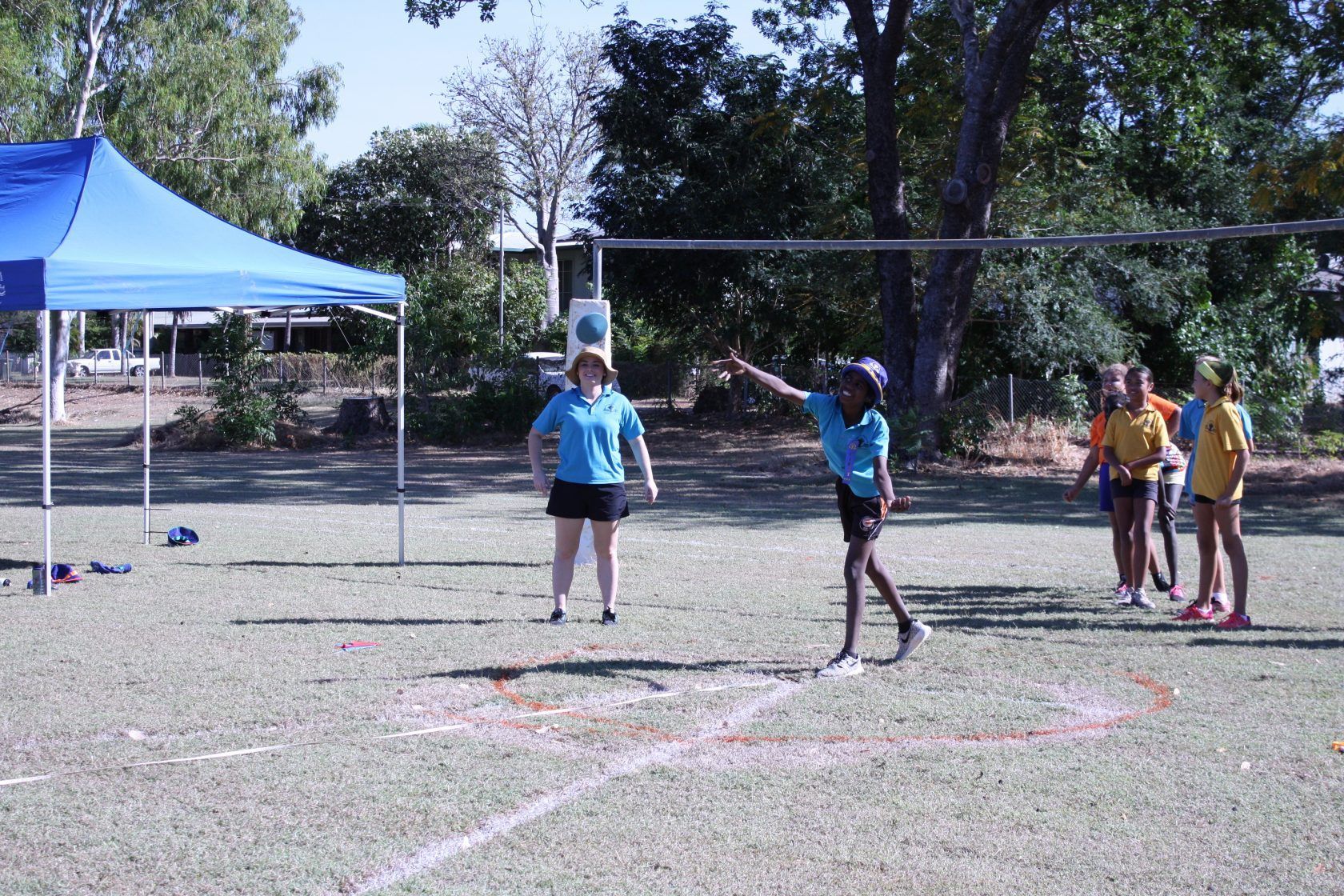 A group of children are playing volleyball in a field.