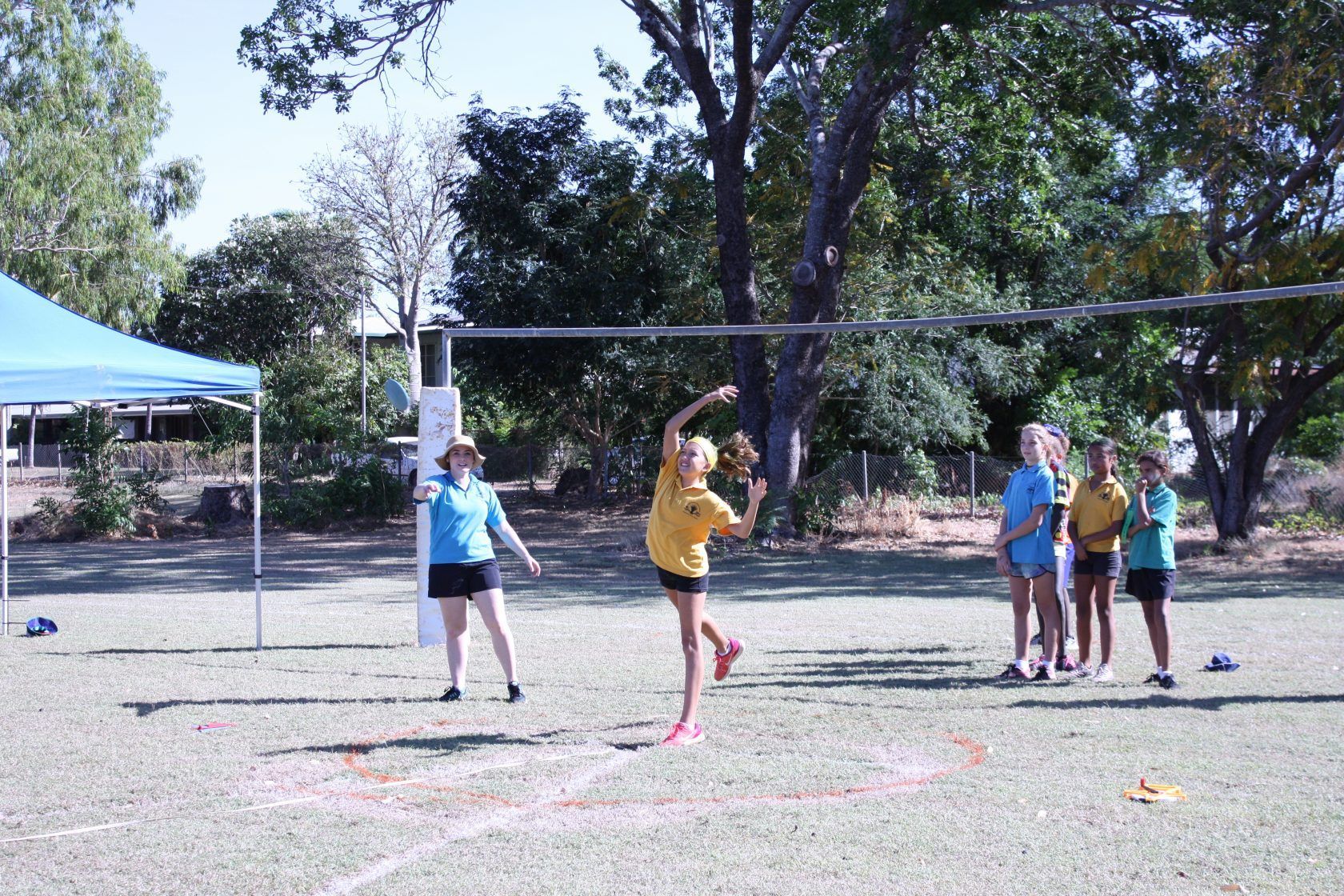 A group of children are playing volleyball on a field.