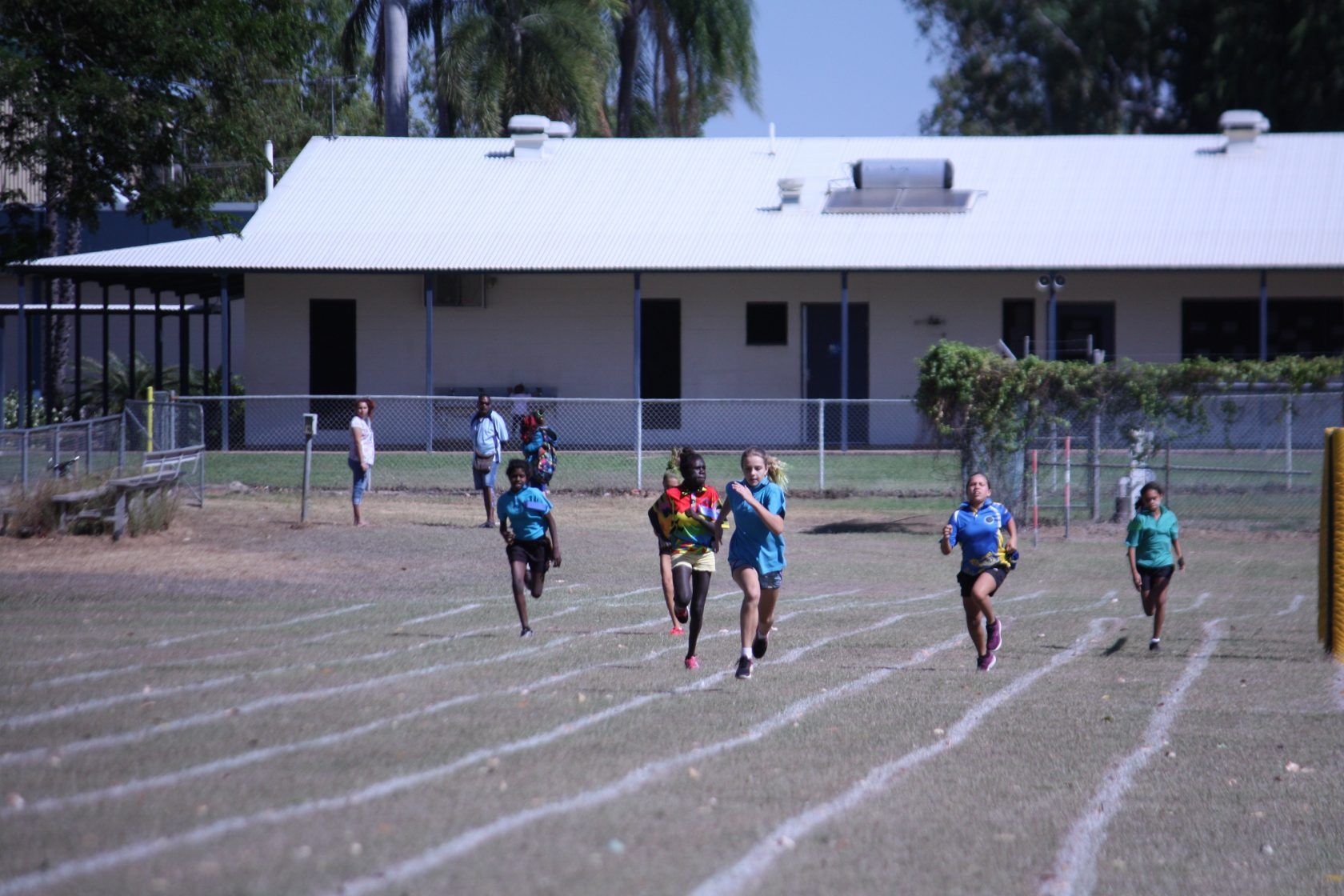 A group of people are running on a track in front of a building