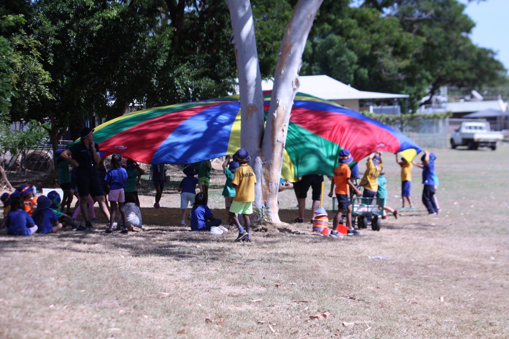 A group of children are playing with a colorful parachute