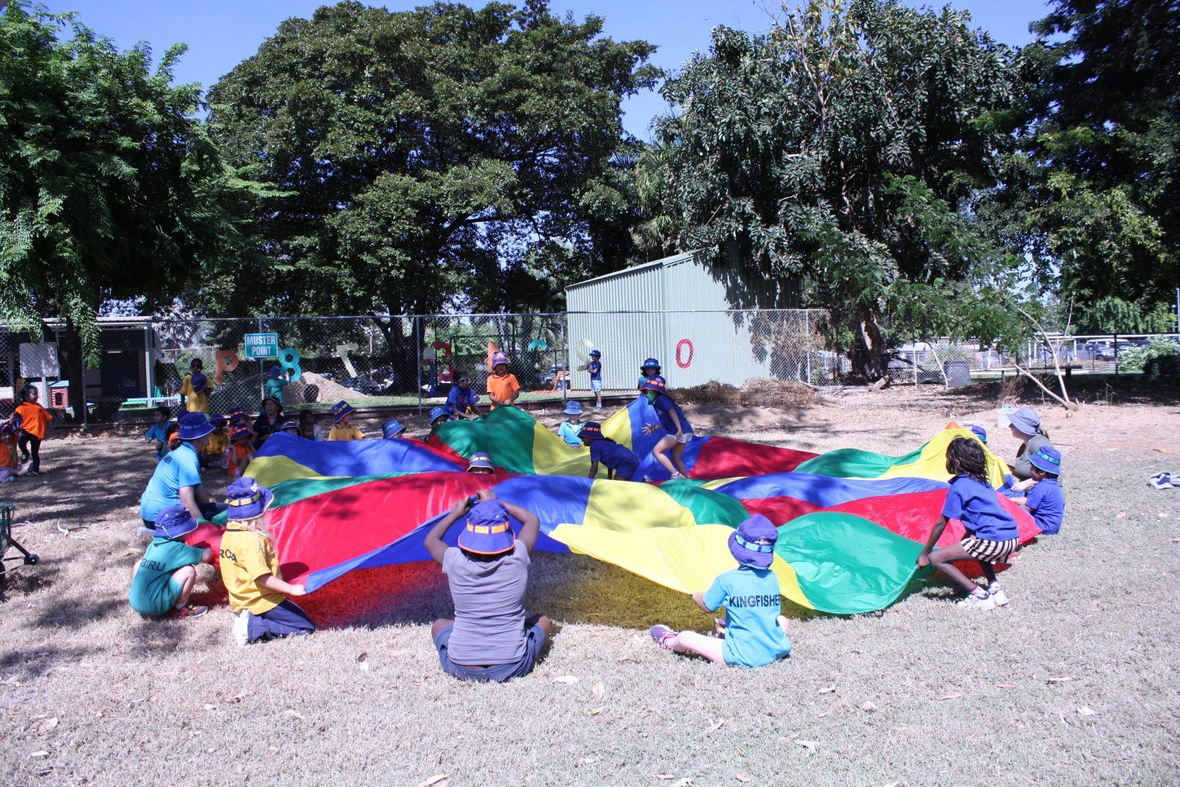 A group of children are playing with parachutes in a park