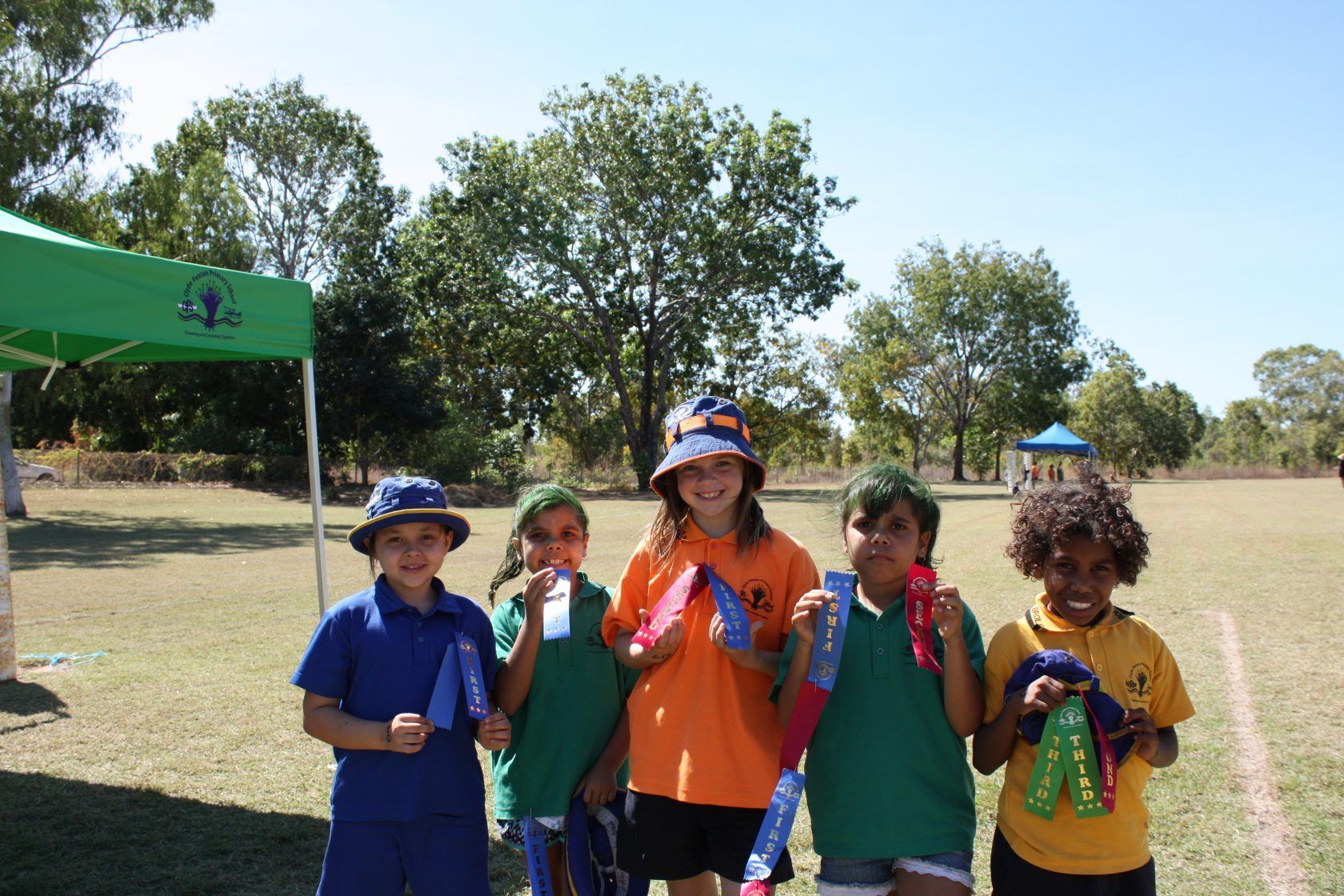 A group of children standing in a field holding medals