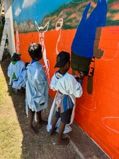 A group of children are painting a mural on a wall.