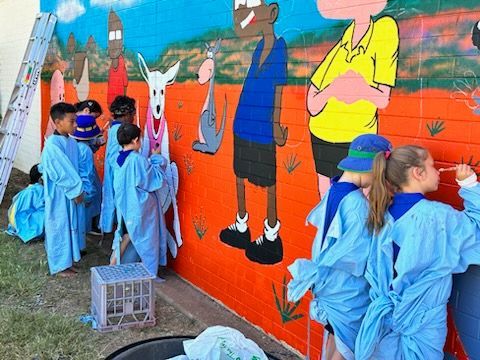 A group of children are painting a mural on a wall.
