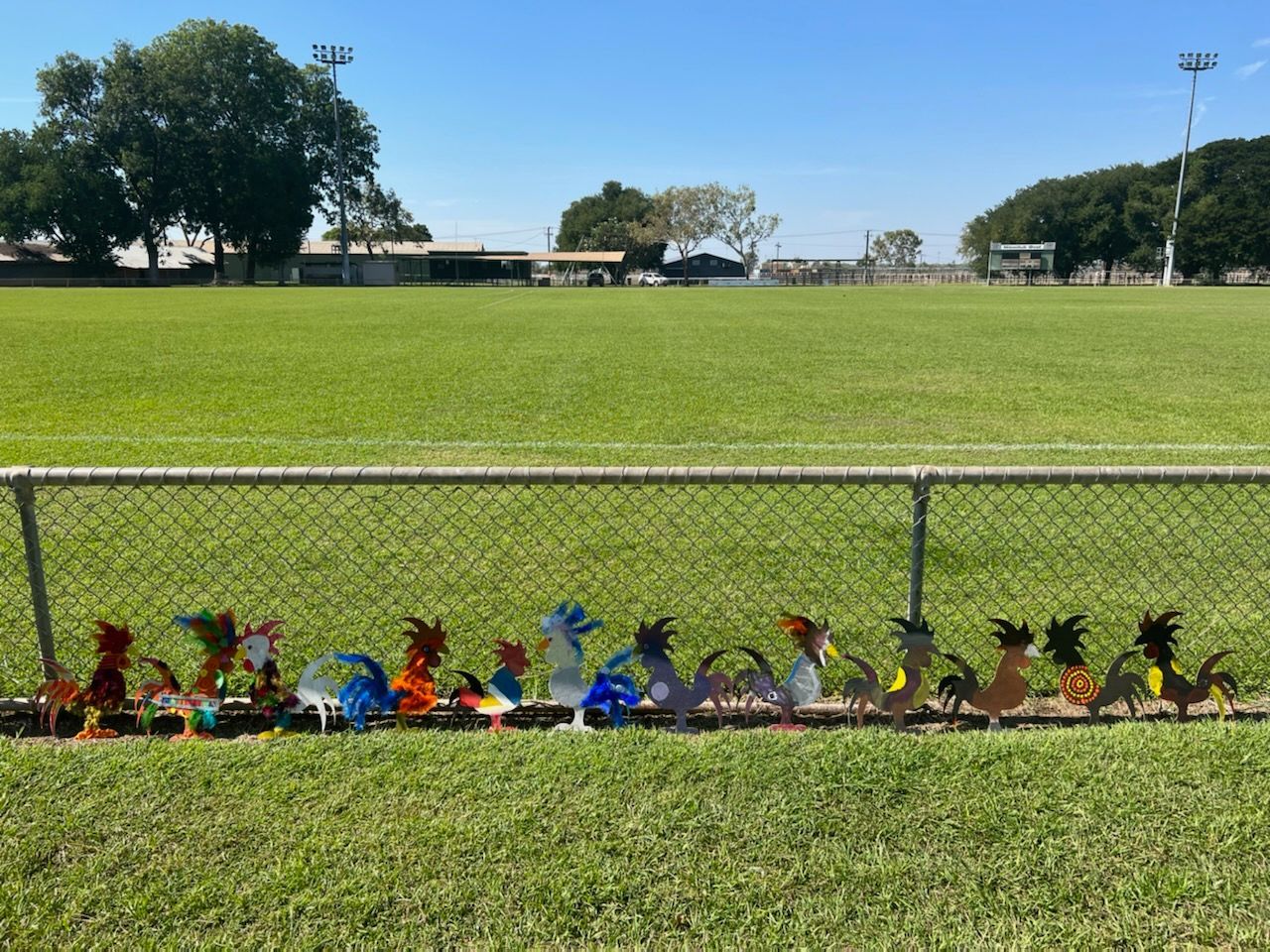 A fence with a bunch of chickens on it