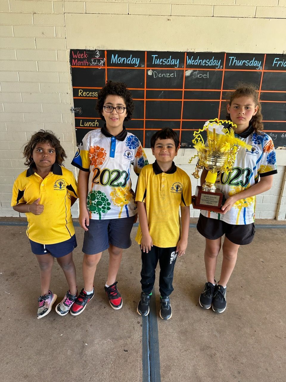 A group of children wearing yellow shirts with the year 2021 on them
