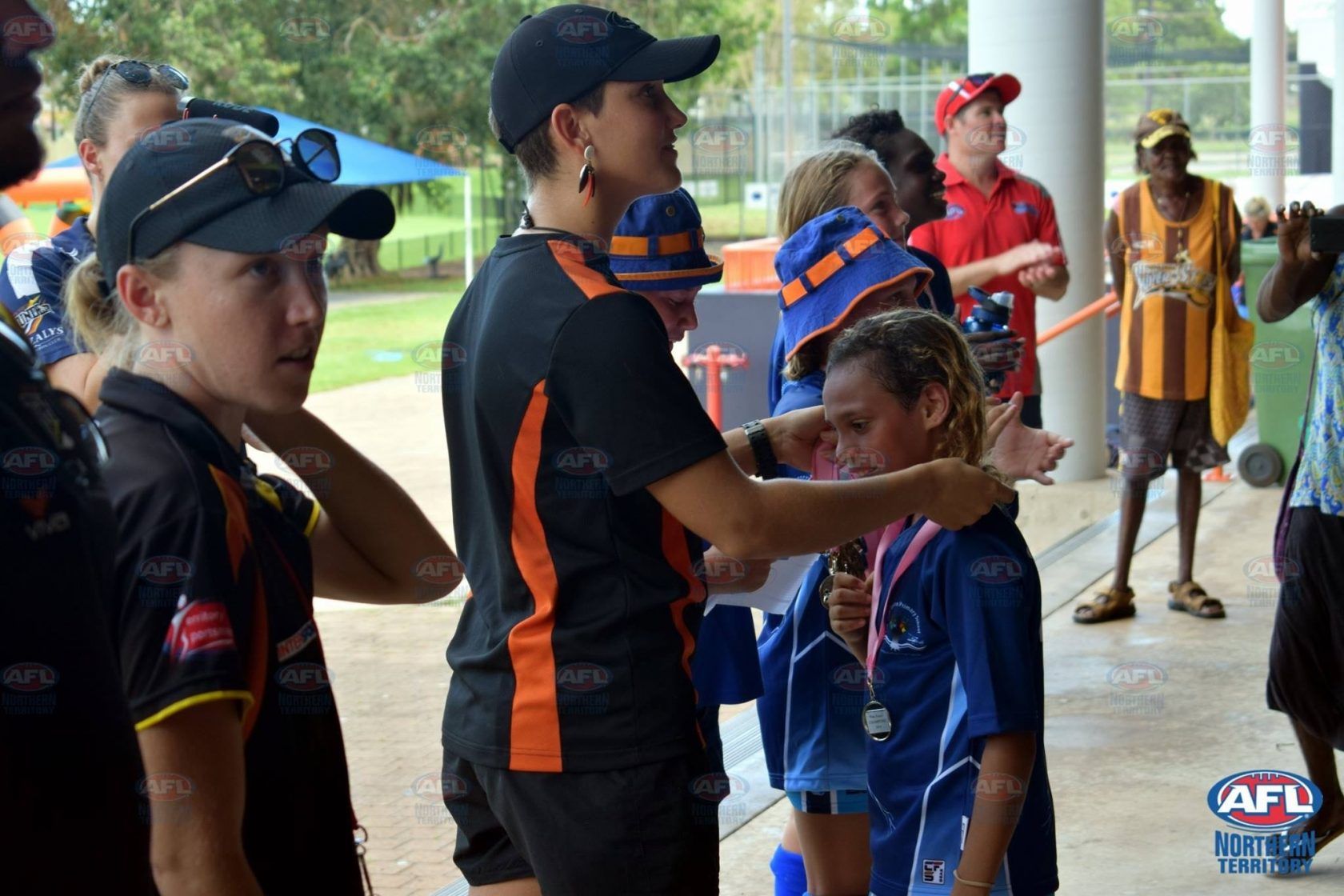 A woman is putting a medal on a young girl 's neck.