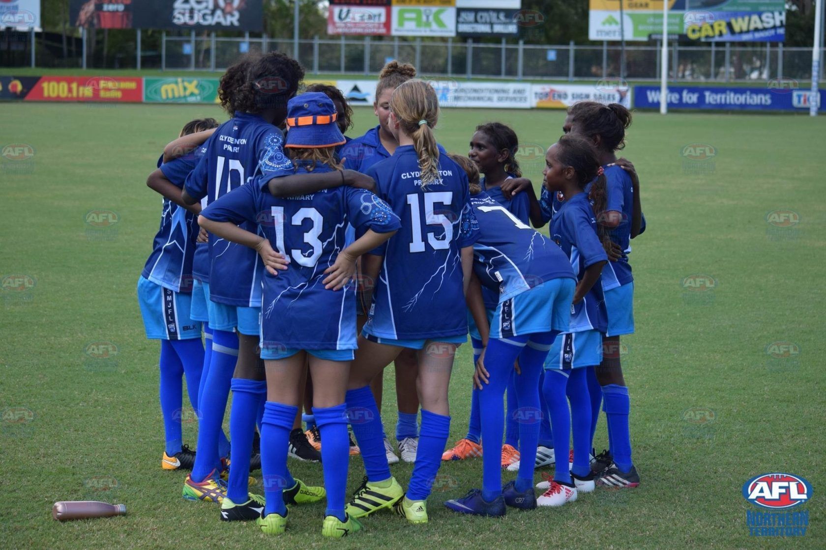 A group of female soccer players are huddled together on a field.