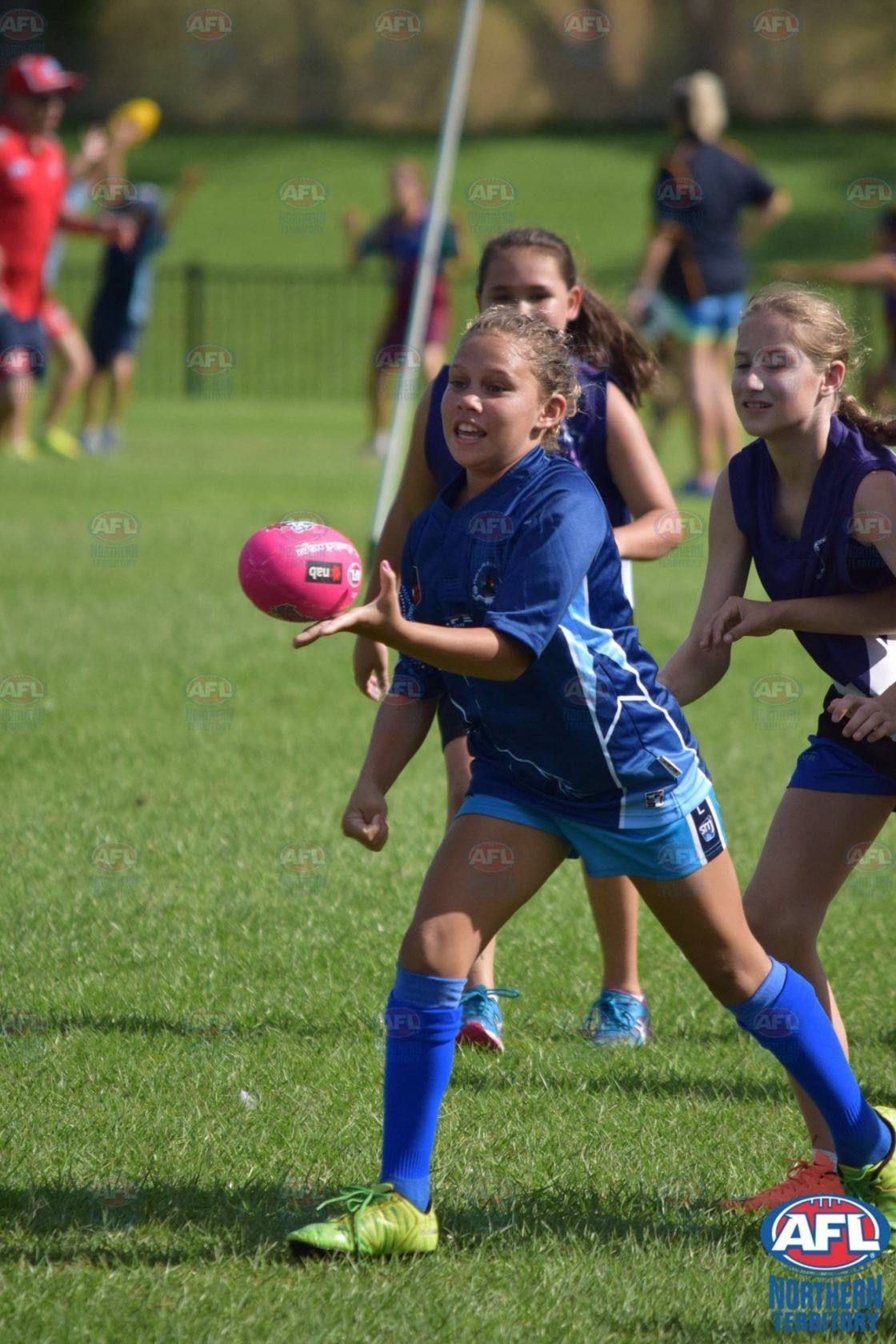 A group of young girls are playing soccer on a field.