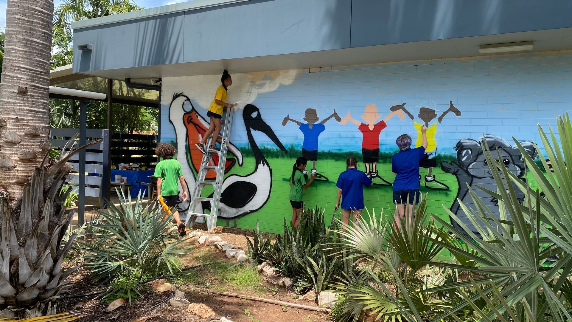 A group of people are painting a mural on the side of a building.