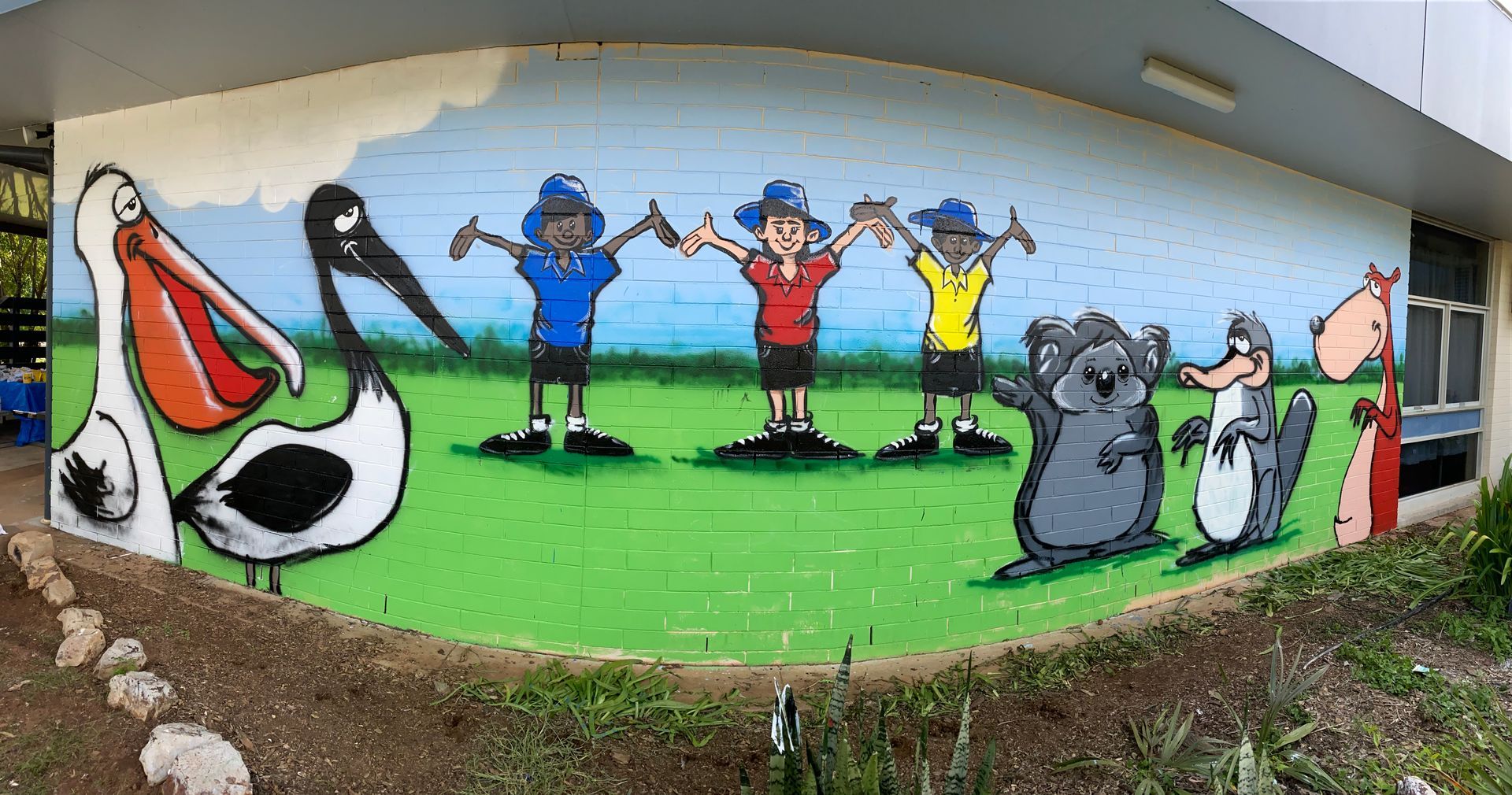 A large mural on the side of a building shows a group of children and animals holding hands.