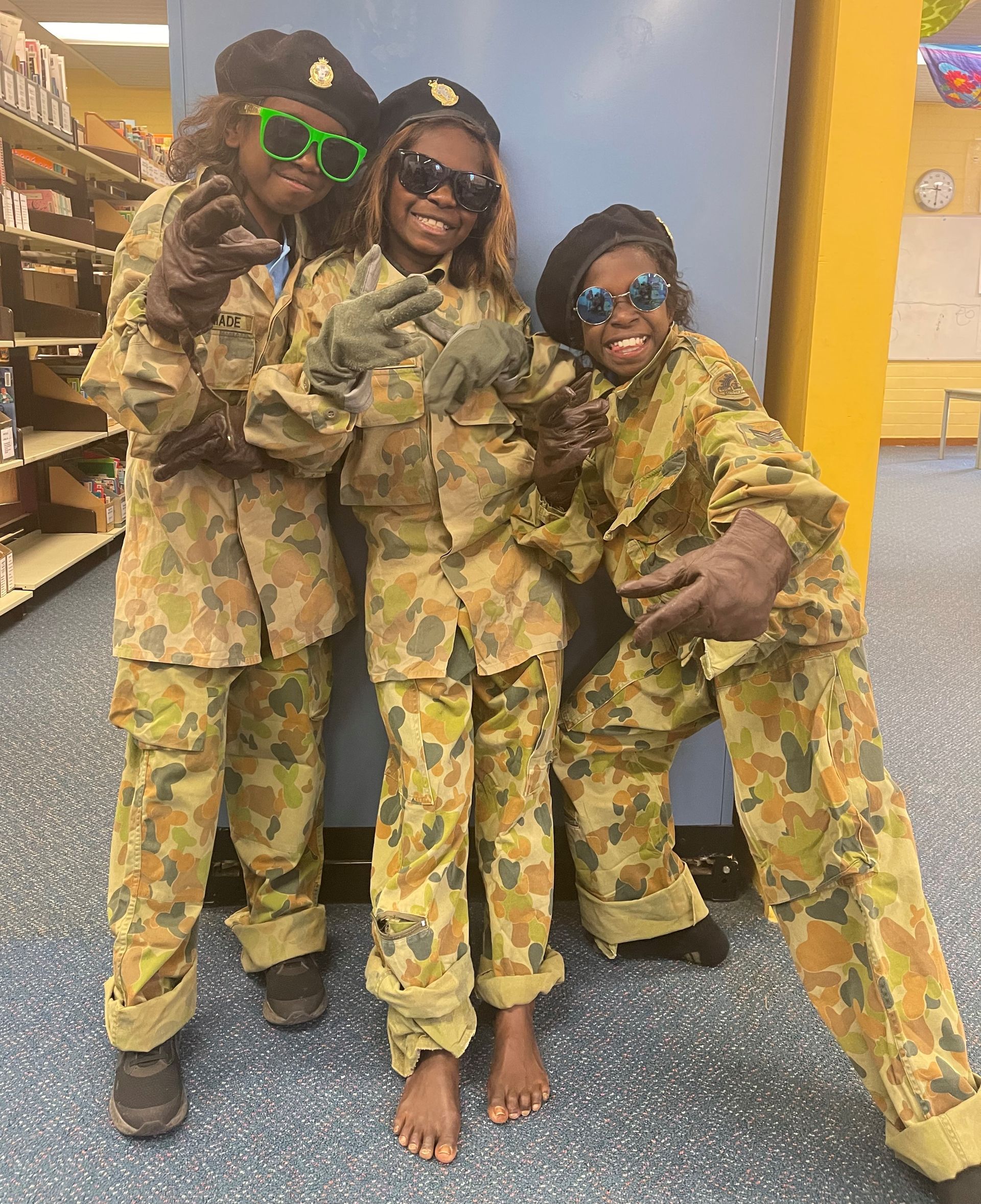Three children dressed in military uniforms and sunglasses are posing for a picture.