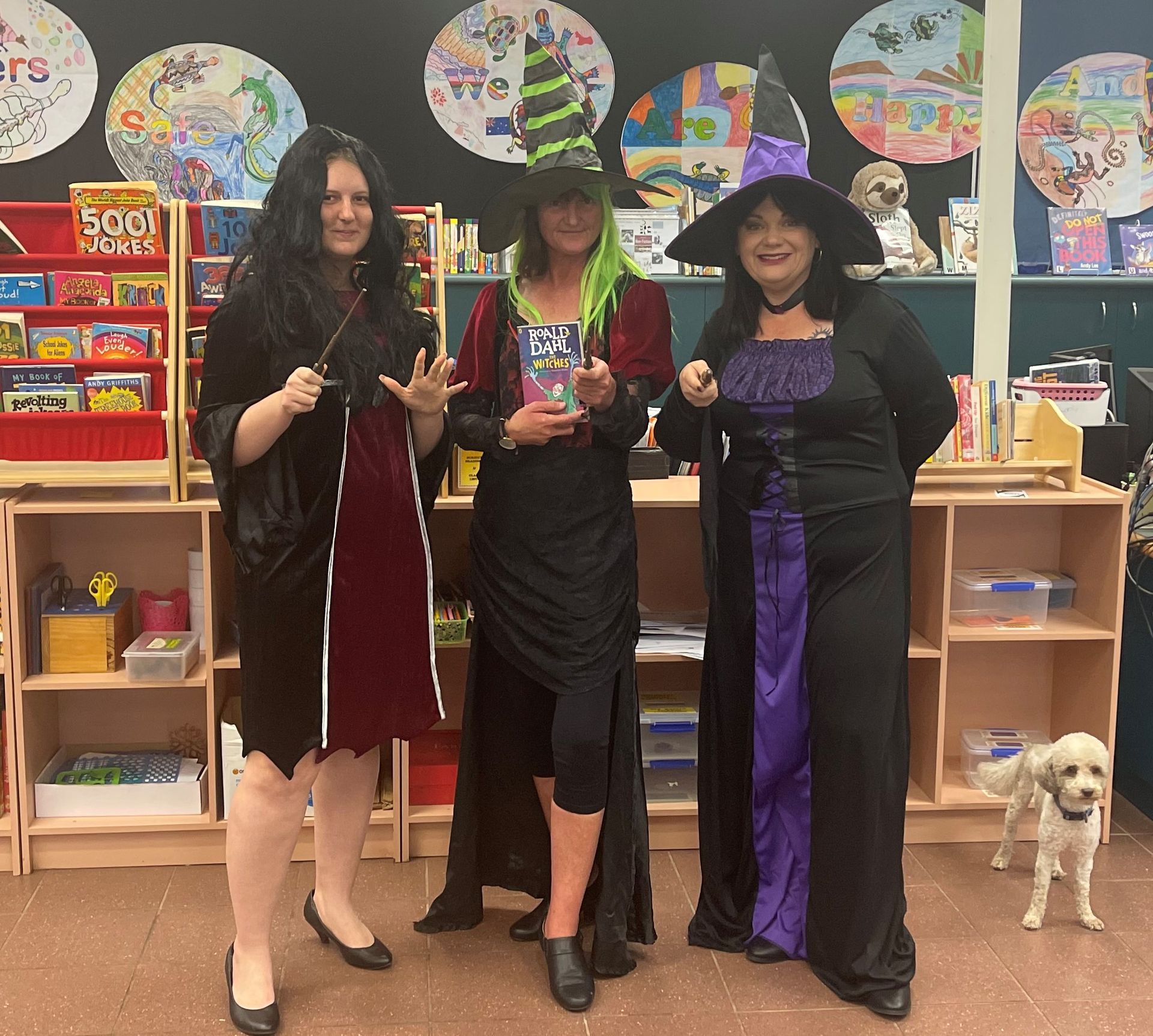Three women in witch costumes are posing for a picture