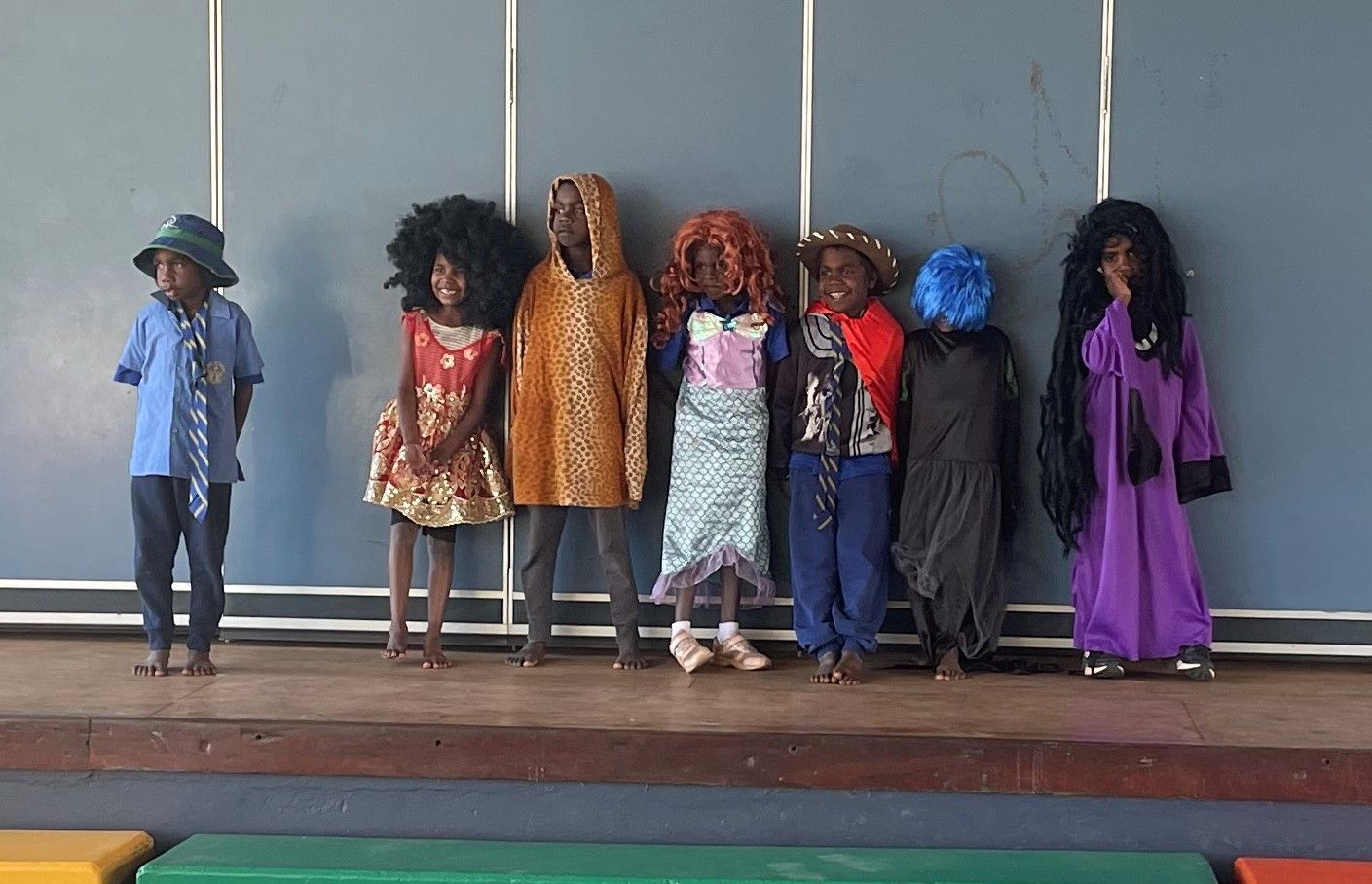 A group of children dressed in costumes are standing on a stage