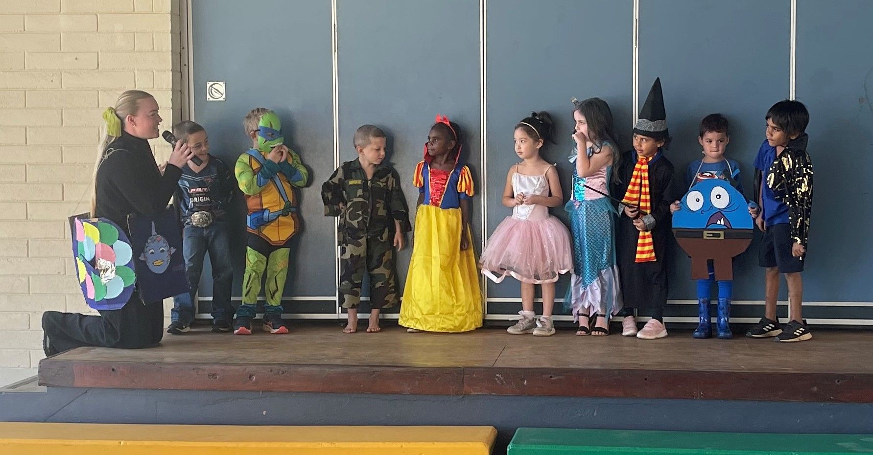 A group of children dressed in costumes are standing on a stage.