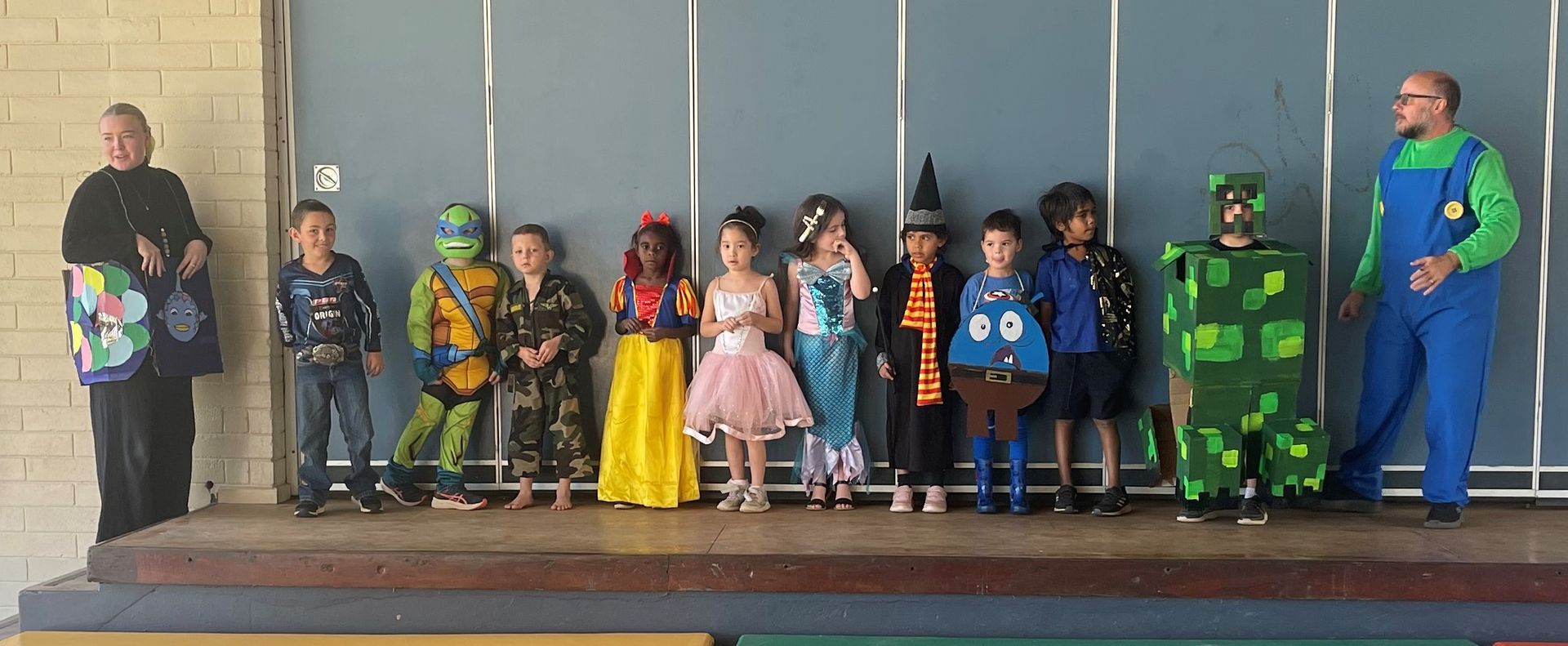 A group of children dressed in costumes are standing on a stage.