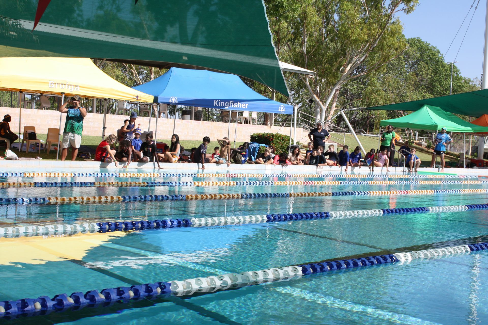 A group of people are standing around a swimming pool