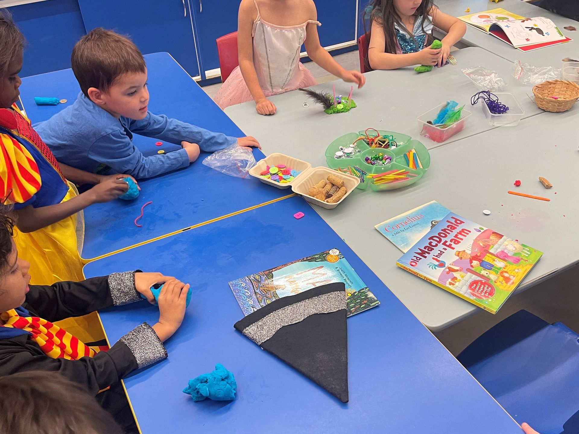 A group of children are sitting at a table playing with play dough.