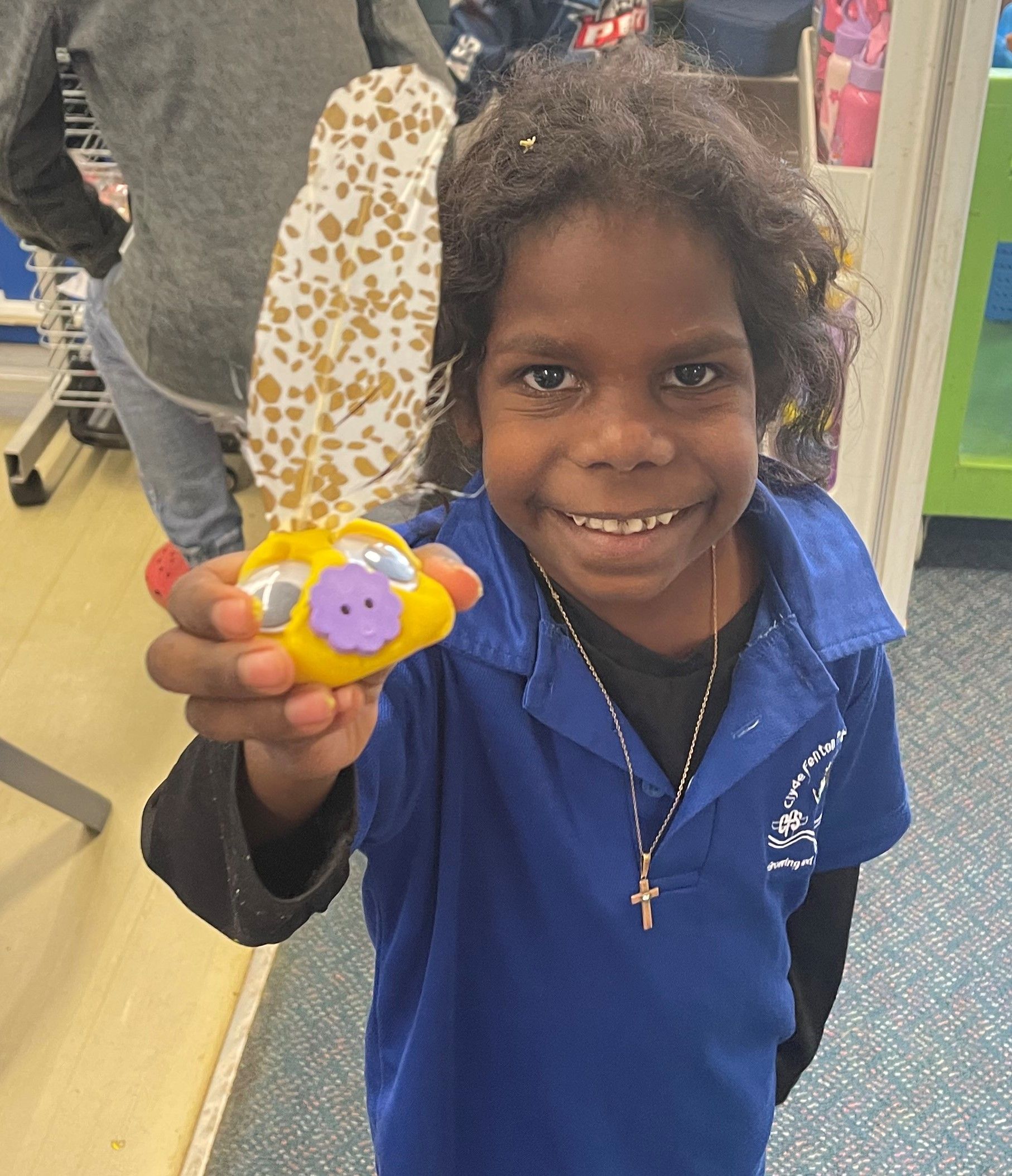 A young girl in a blue shirt is holding a toy in her hand