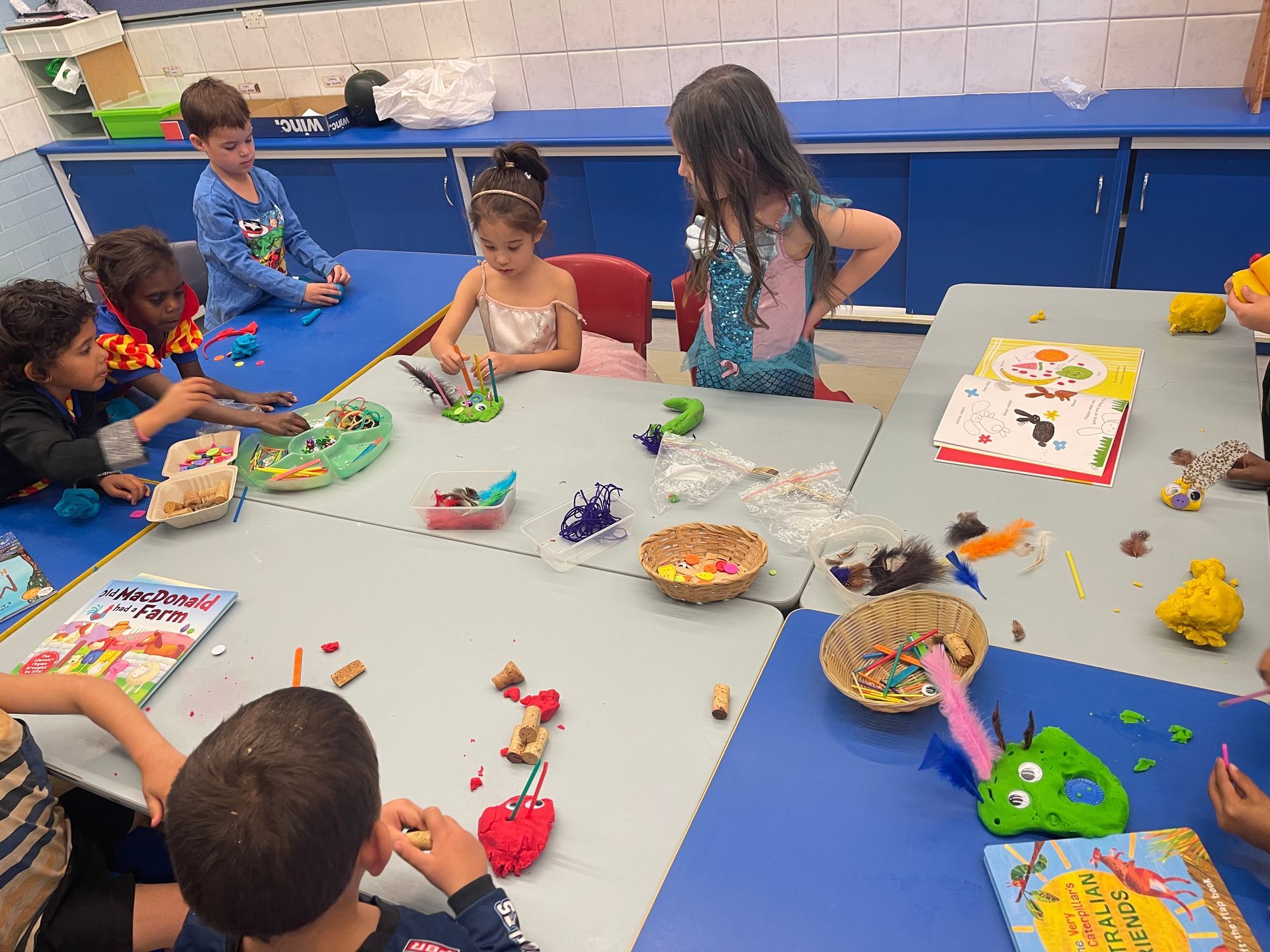 A group of children are sitting around a table playing with play dough.