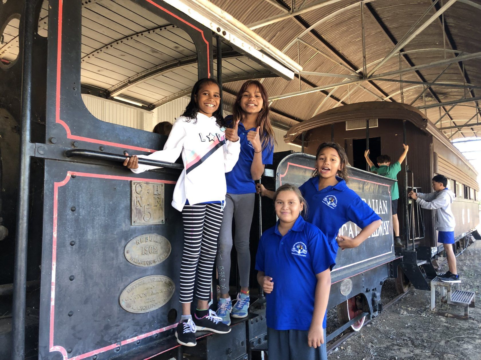 A group of children are posing for a picture in front of a train.