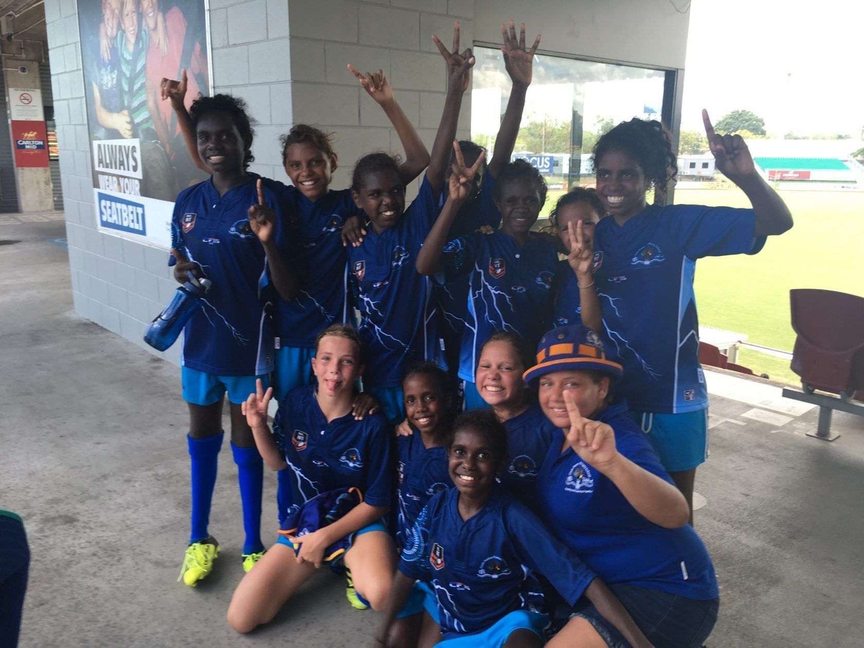 A group of young girls in blue shirts are posing for a picture
