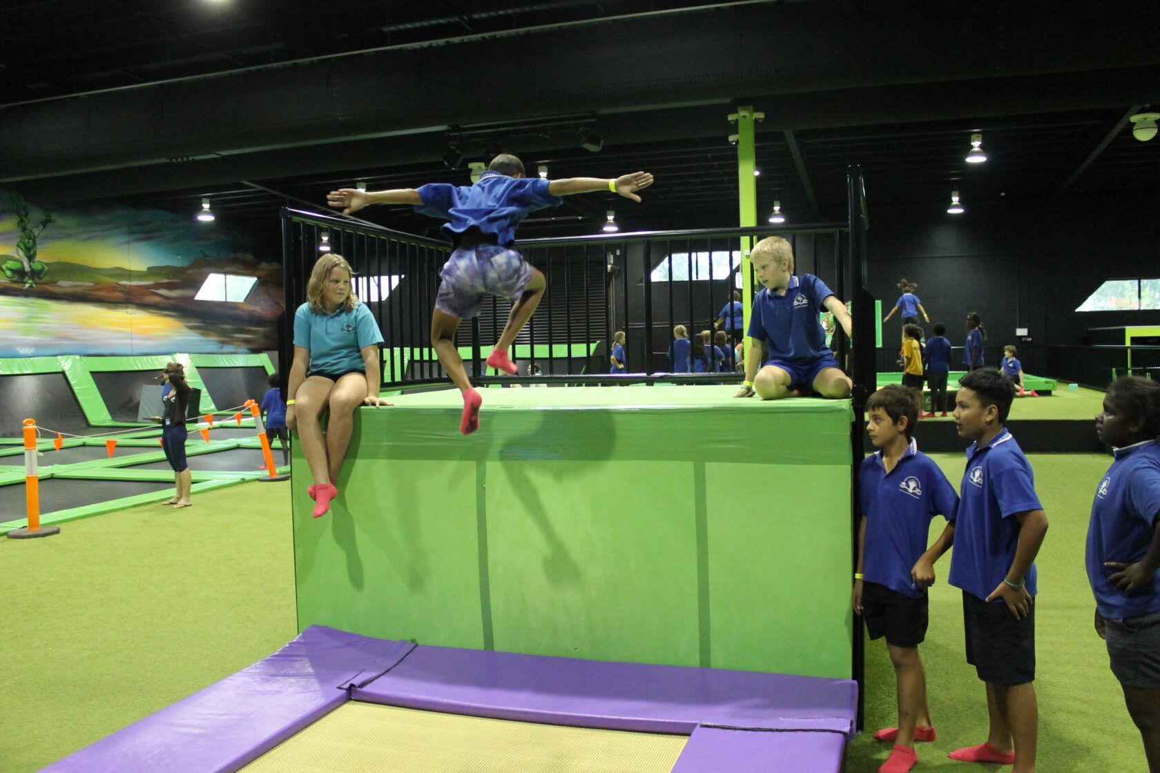 A group of children are playing on a trampoline in a gym.