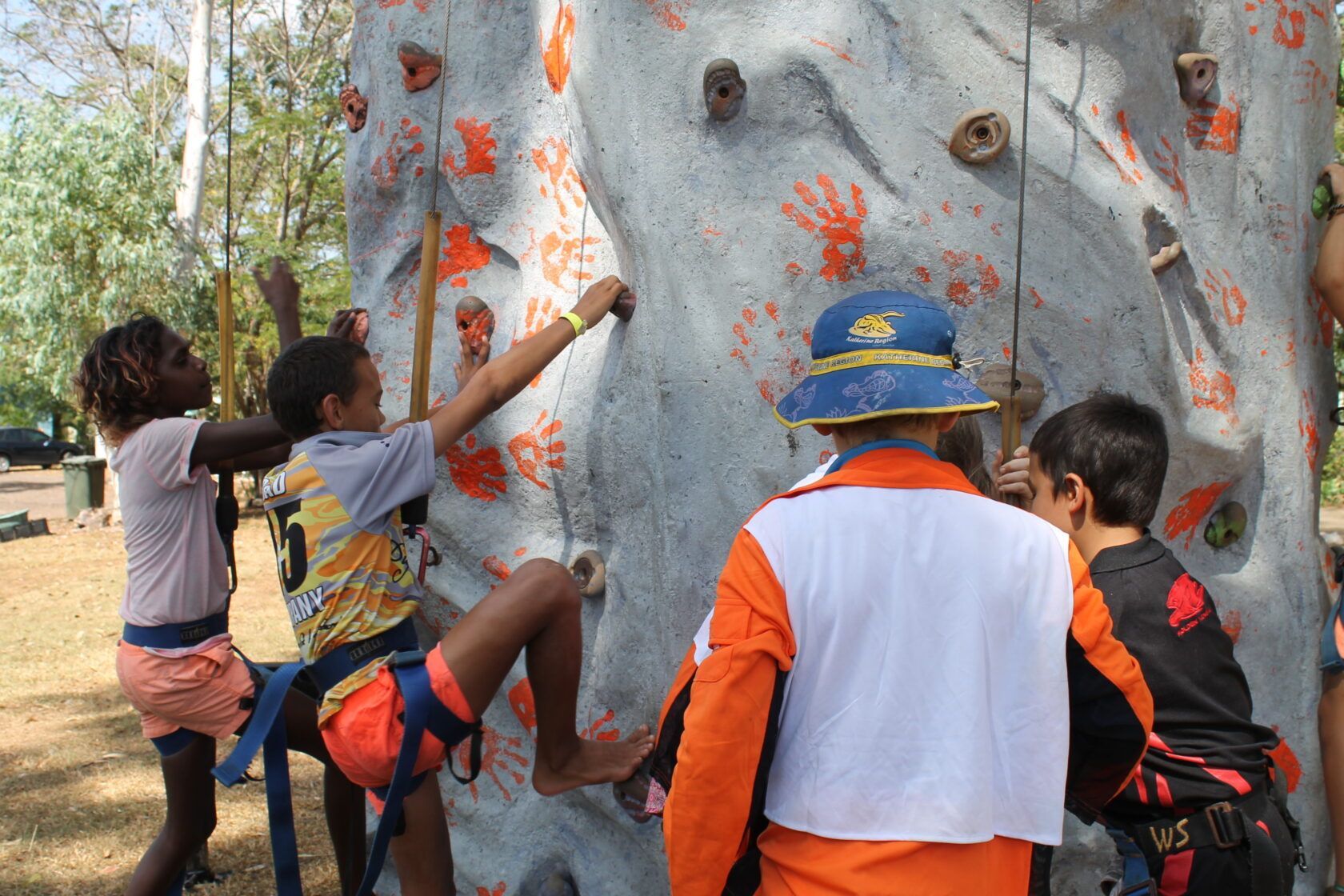 A group of children are climbing a rock wall.