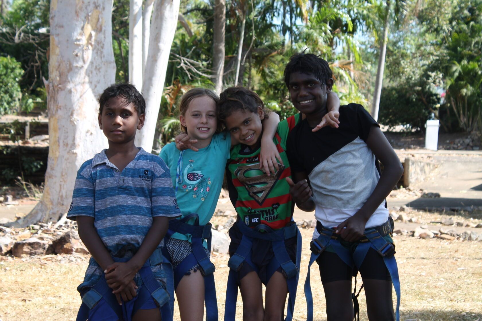 A group of children posing for a picture with one wearing a superman shirt