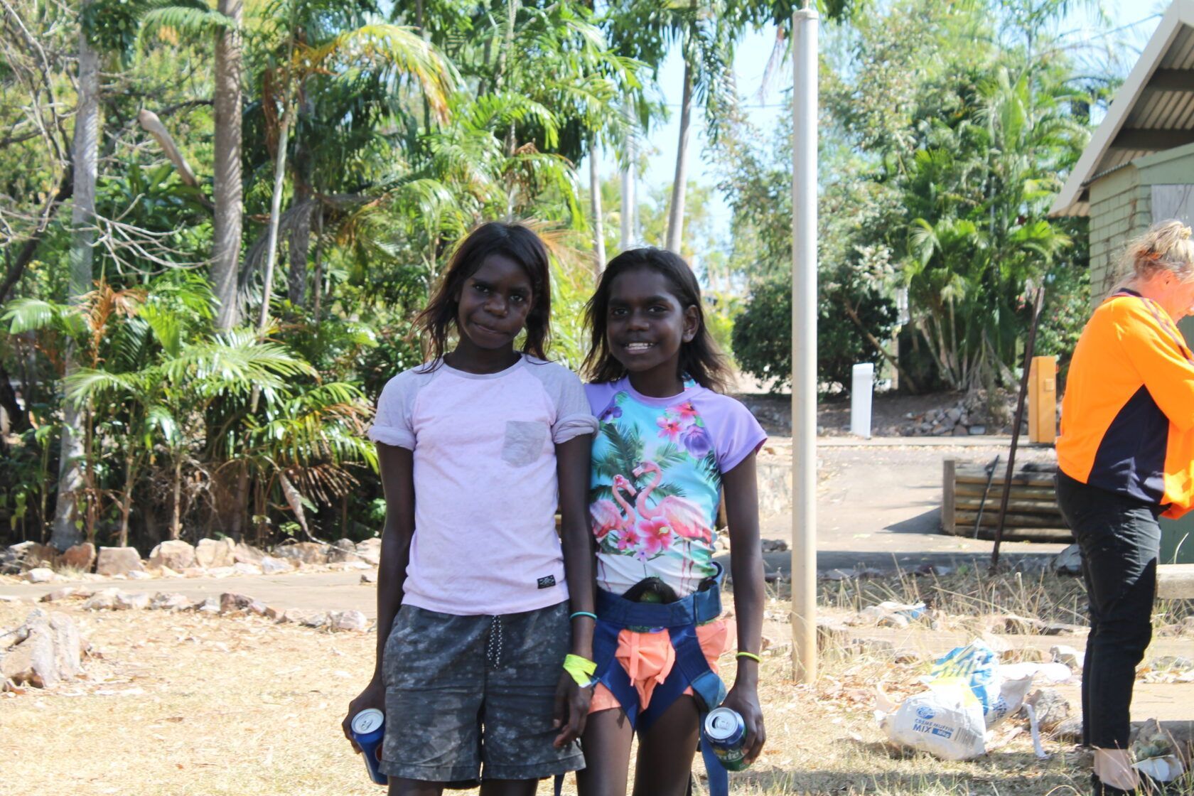 Two young girls are standing next to each other in a field holding hands.
