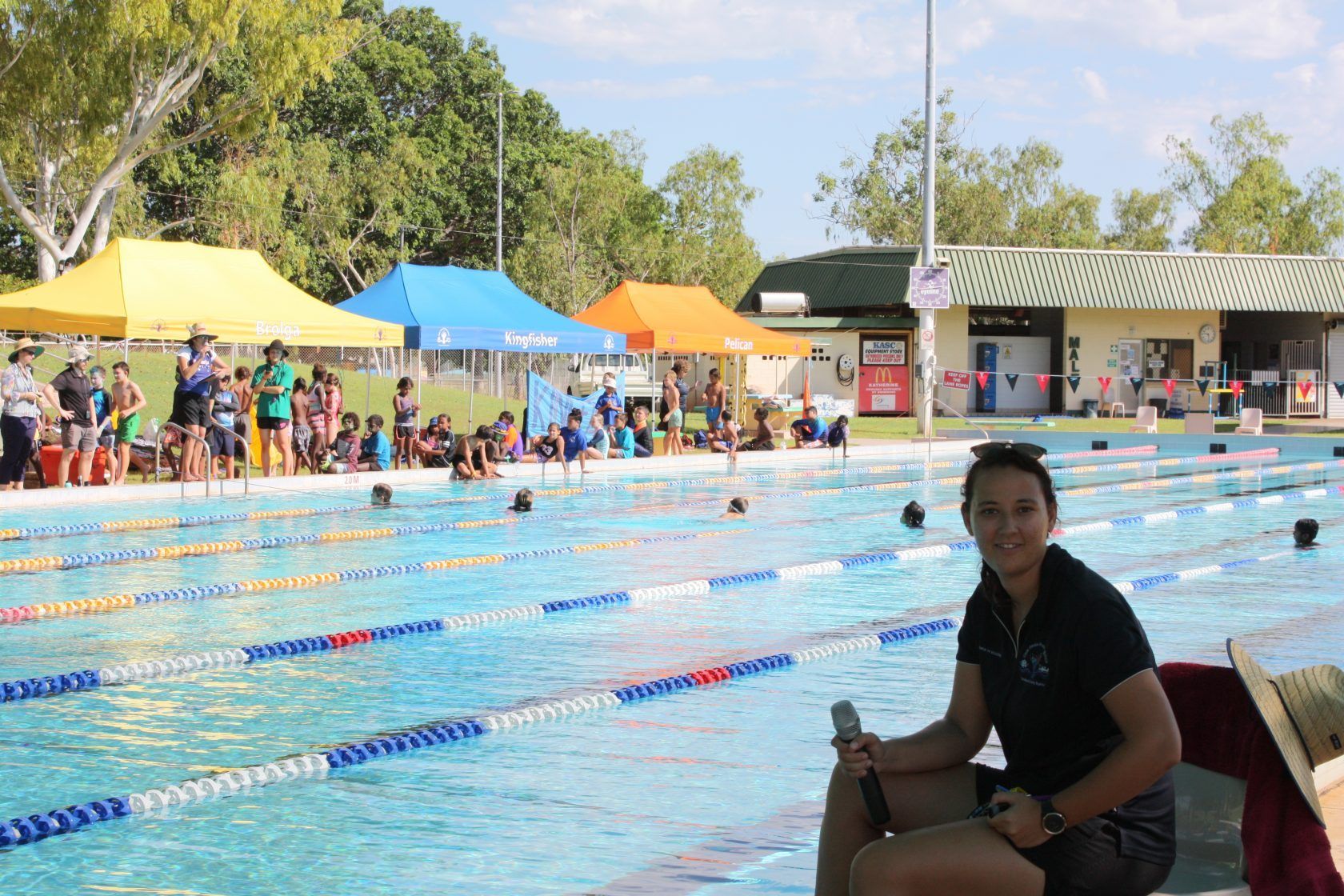 A woman is sitting on the edge of a swimming pool.