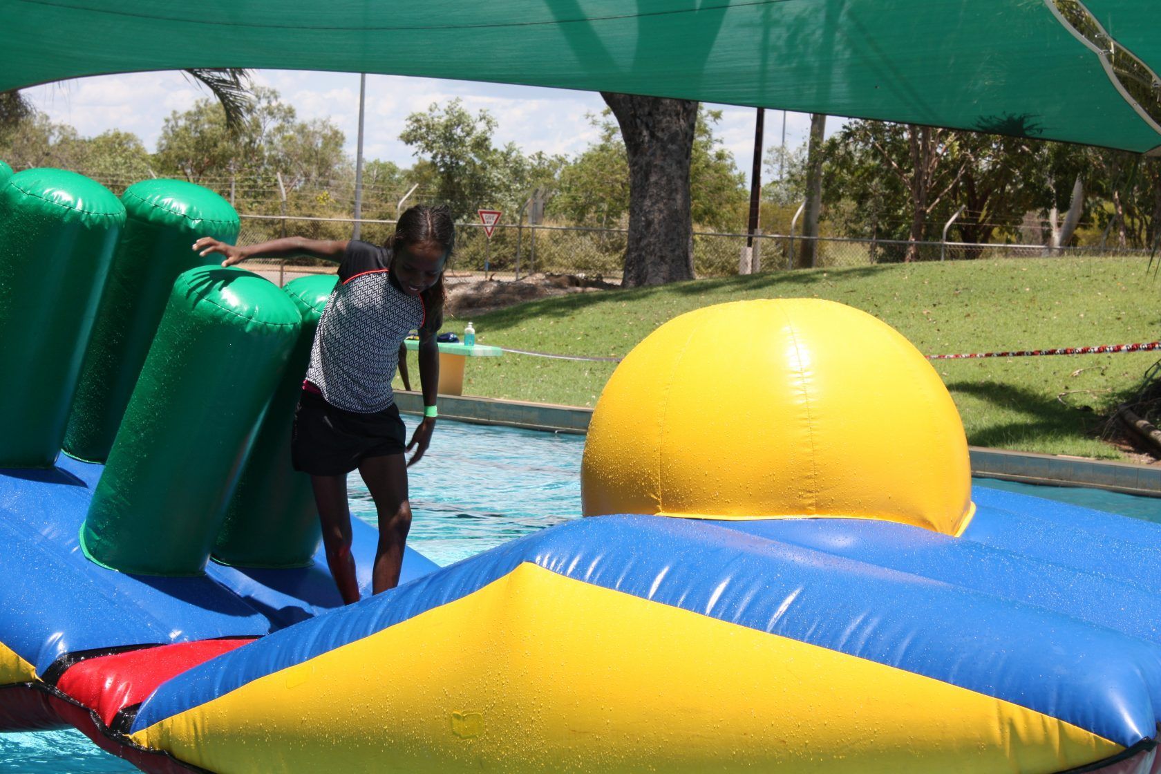 A girl is playing with a large inflatable ball in a pool