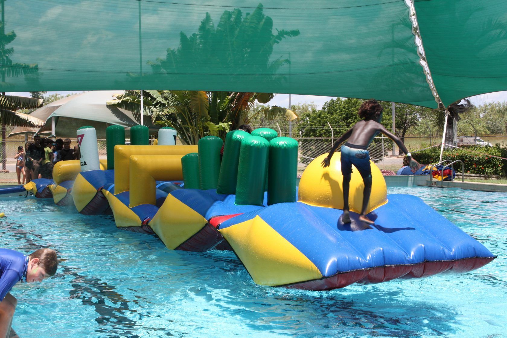 A boy is jumping on an inflatable raft in a pool